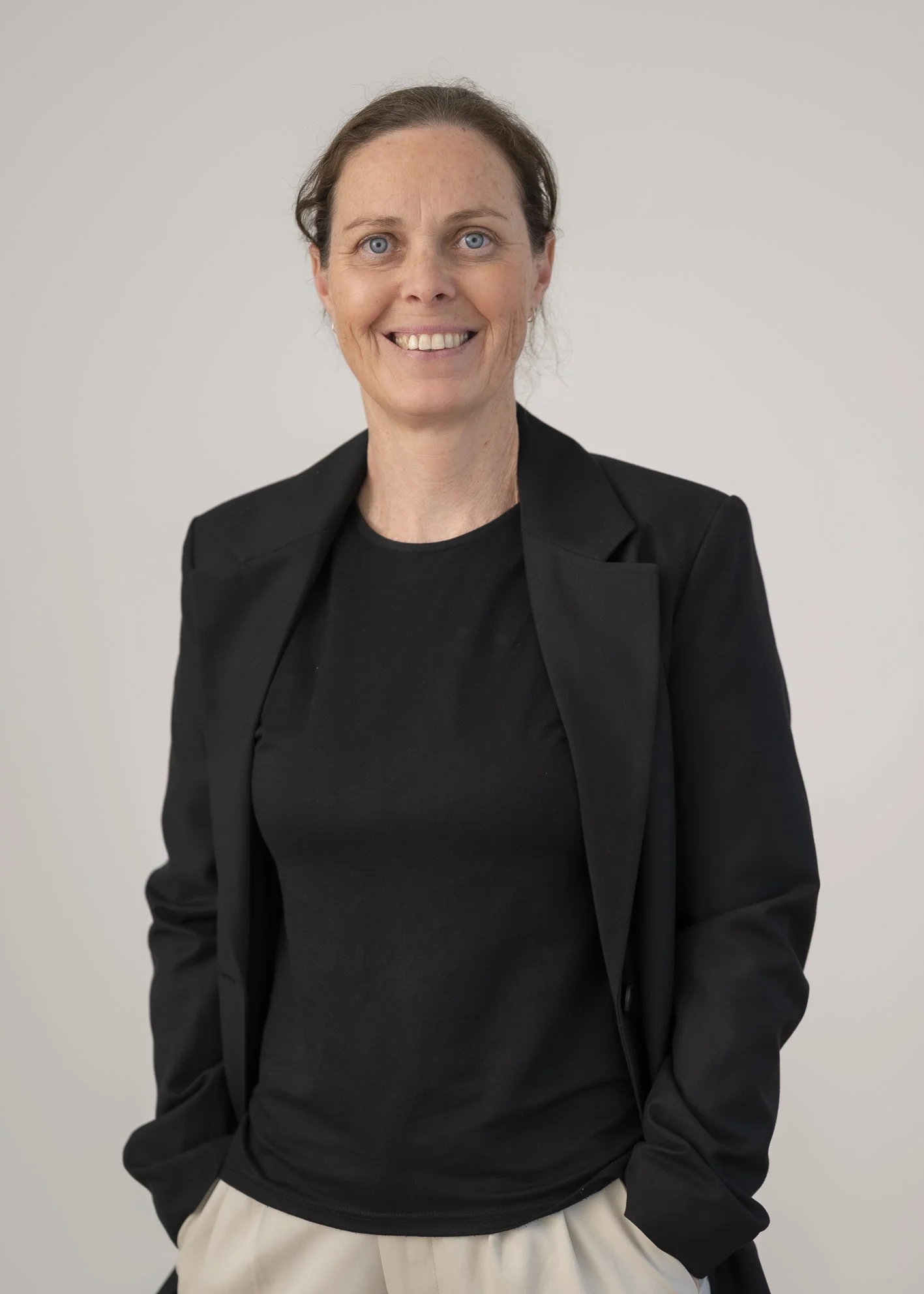 Portrait of Rachel Anderson, Medical Receptionist, smiling warmly against a neutral grey background.