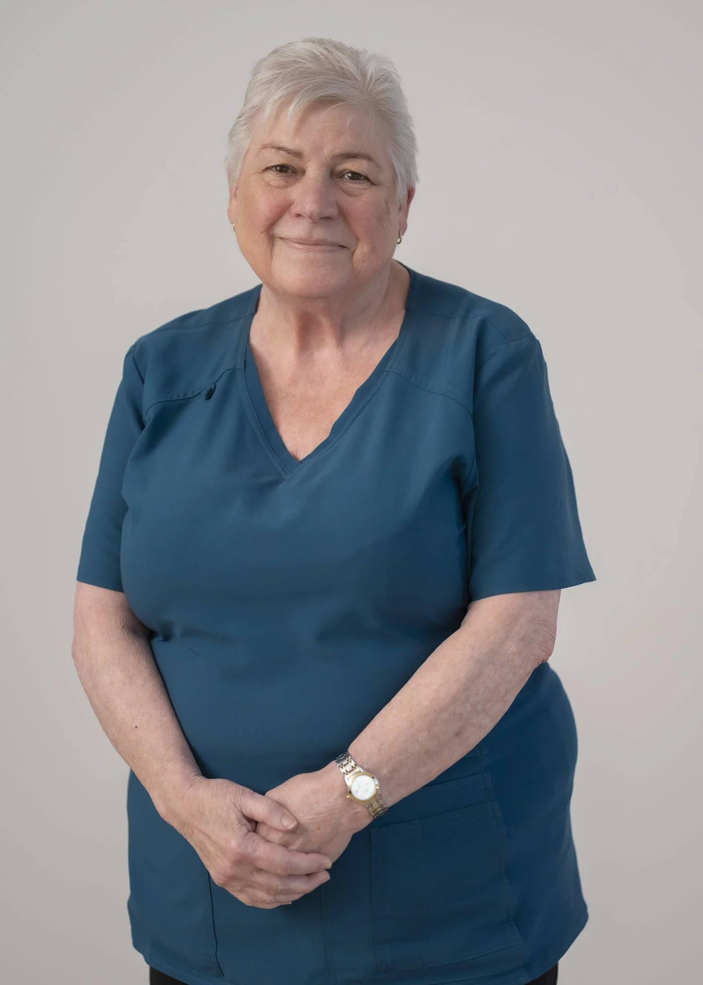Portrait of Barbara Sangster, Practice Nurse, standing in teal scrubs with a calm and approachable expression.