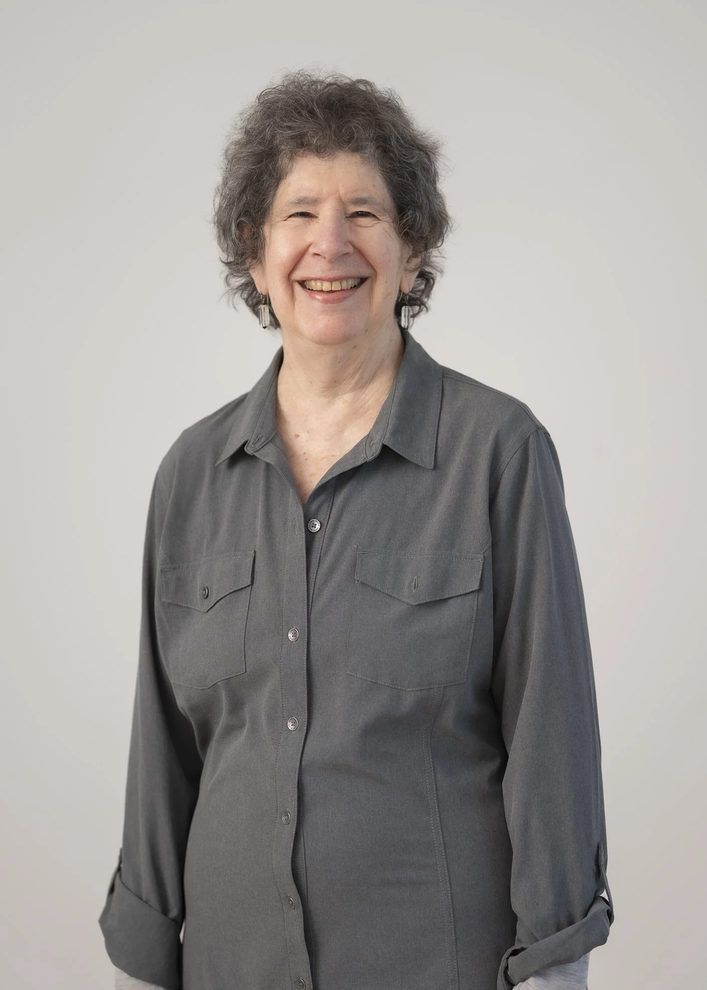 Portrait of Dr Nancy Carter, Trustee, standing against a neutral grey background.