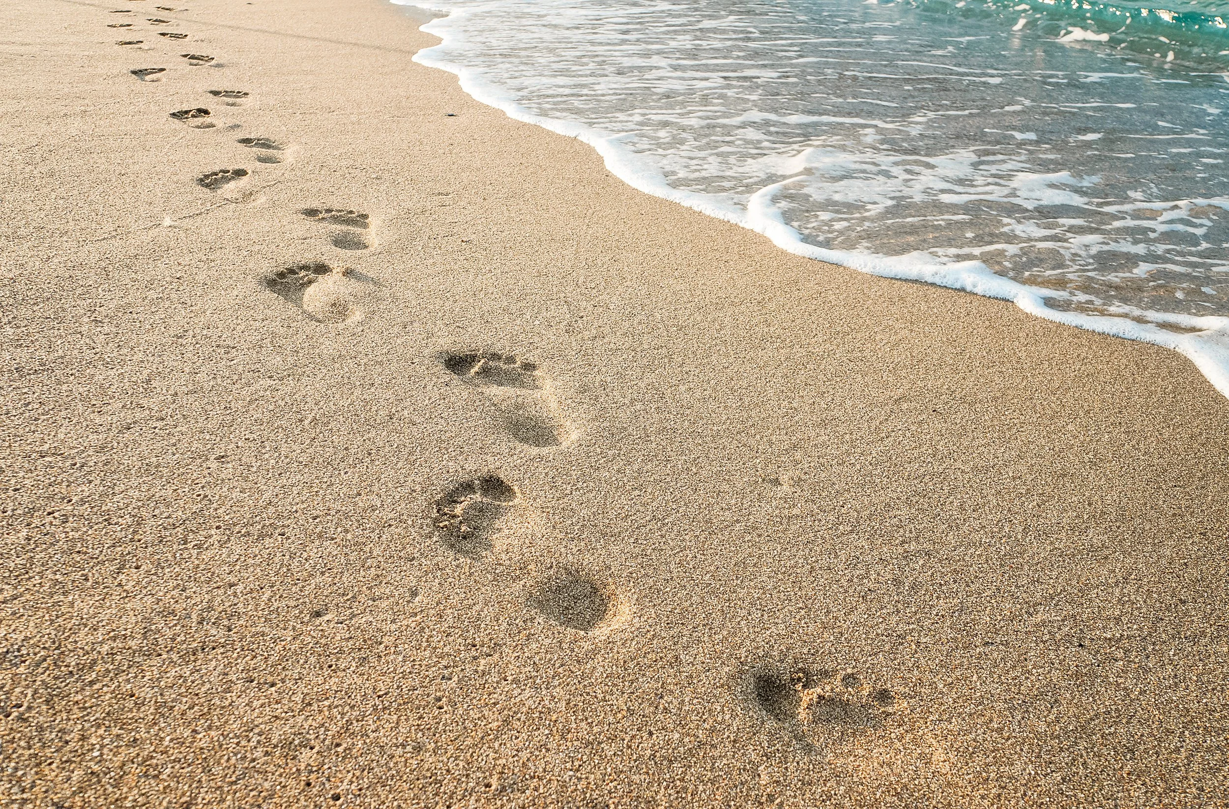 An image of footprints in the sand at the beach