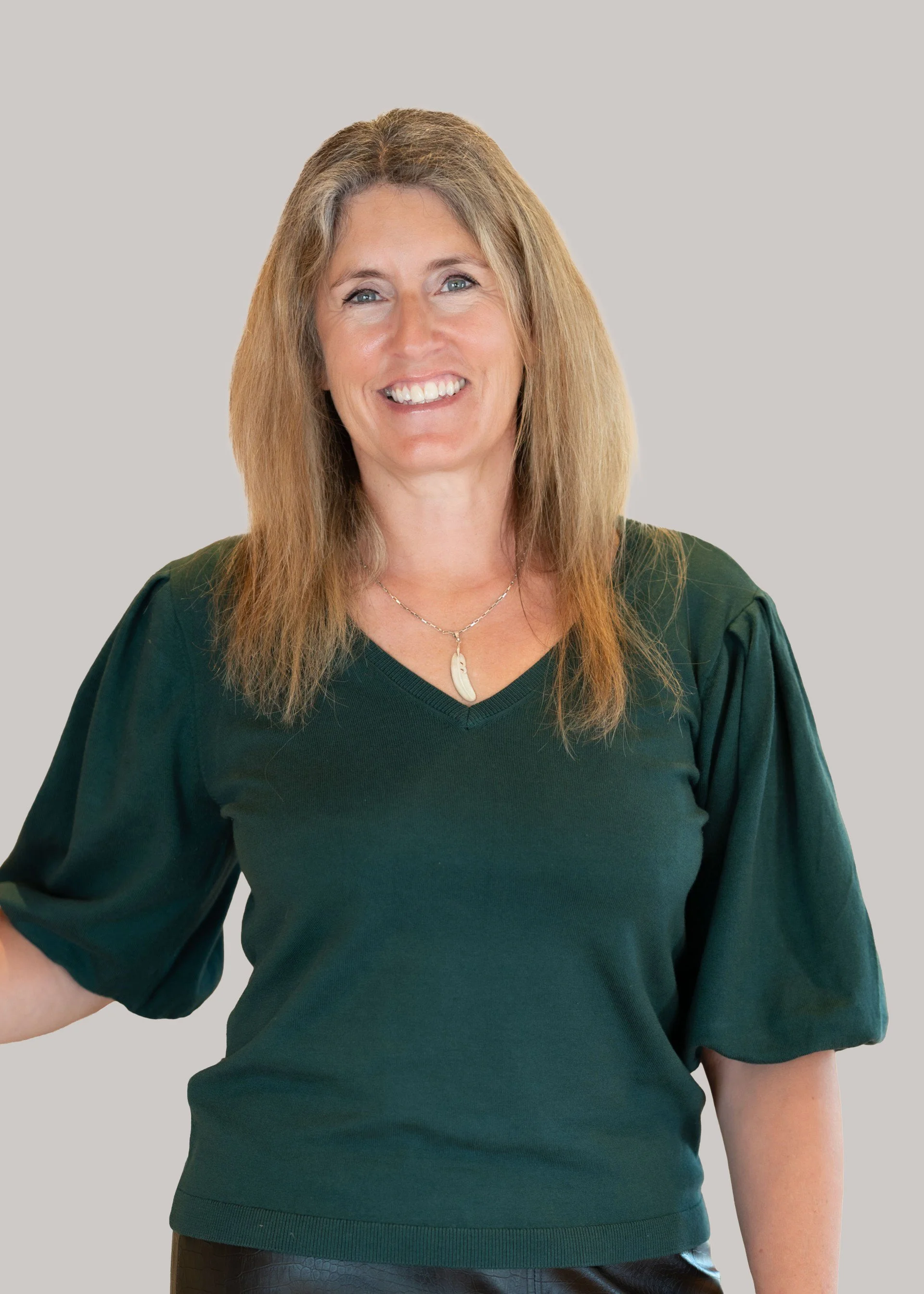 Portrait of Dr Zoe Douglass, General Practitioner, smiling warmly in a dark green top against a neutral background.