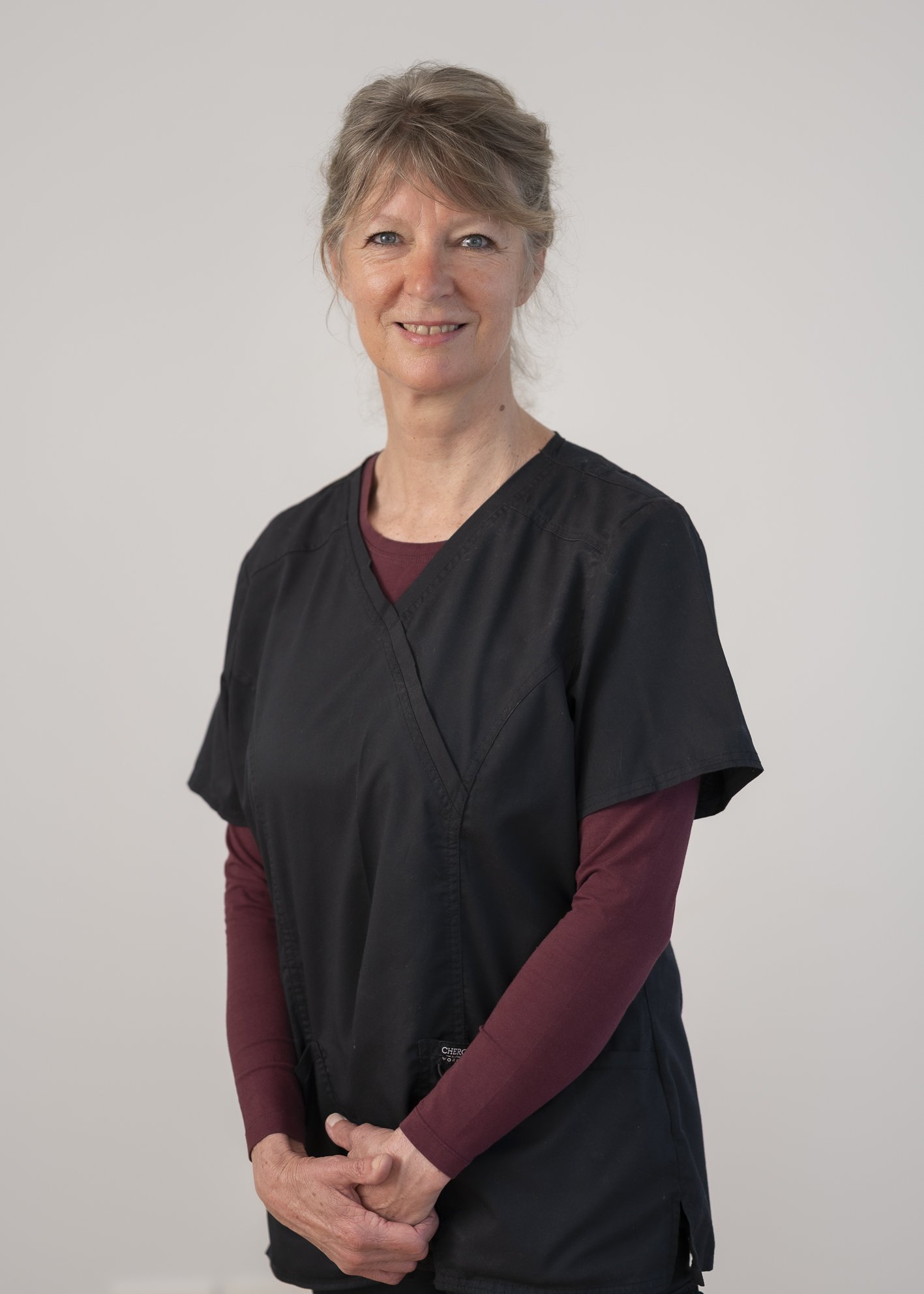 Portrait of Janet Marsden, Specialist Community Nurse against a plain light grey backround.  Janet’s calm and compassionate presence reflects her 25+ years of experience supporting clients and their families through complex nursing care.