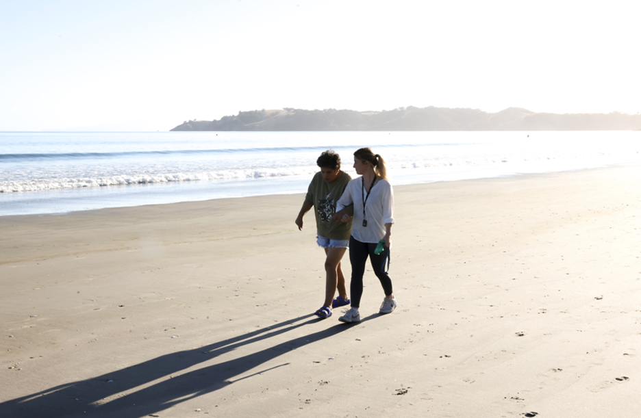 A community service worker and her patient are getting some exercise by walking on Onetangi beach at sunset.