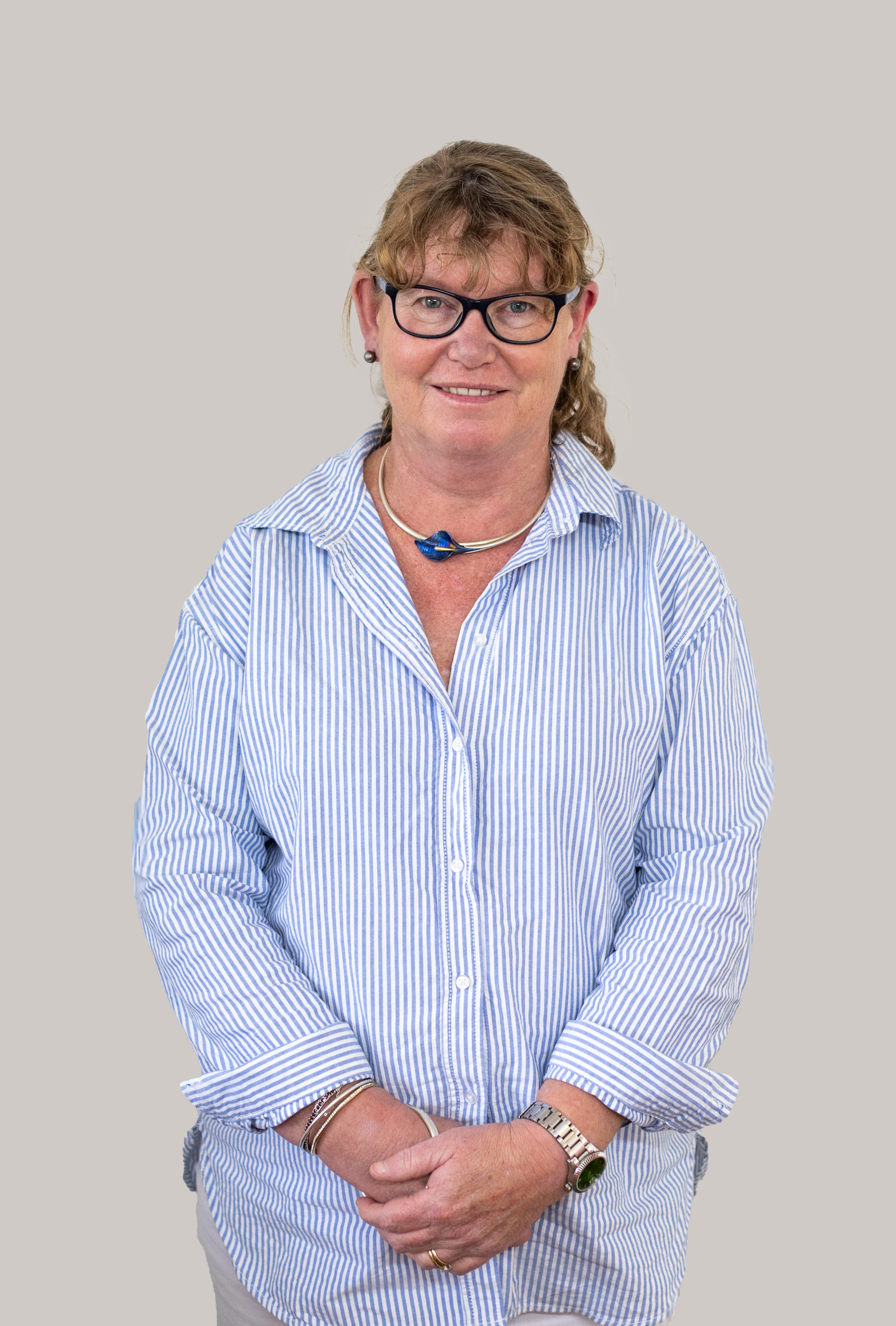 Portrait of Erica Wright, Nurse Practitioner, standing in a striped shirt and glasses with a friendly smile.
