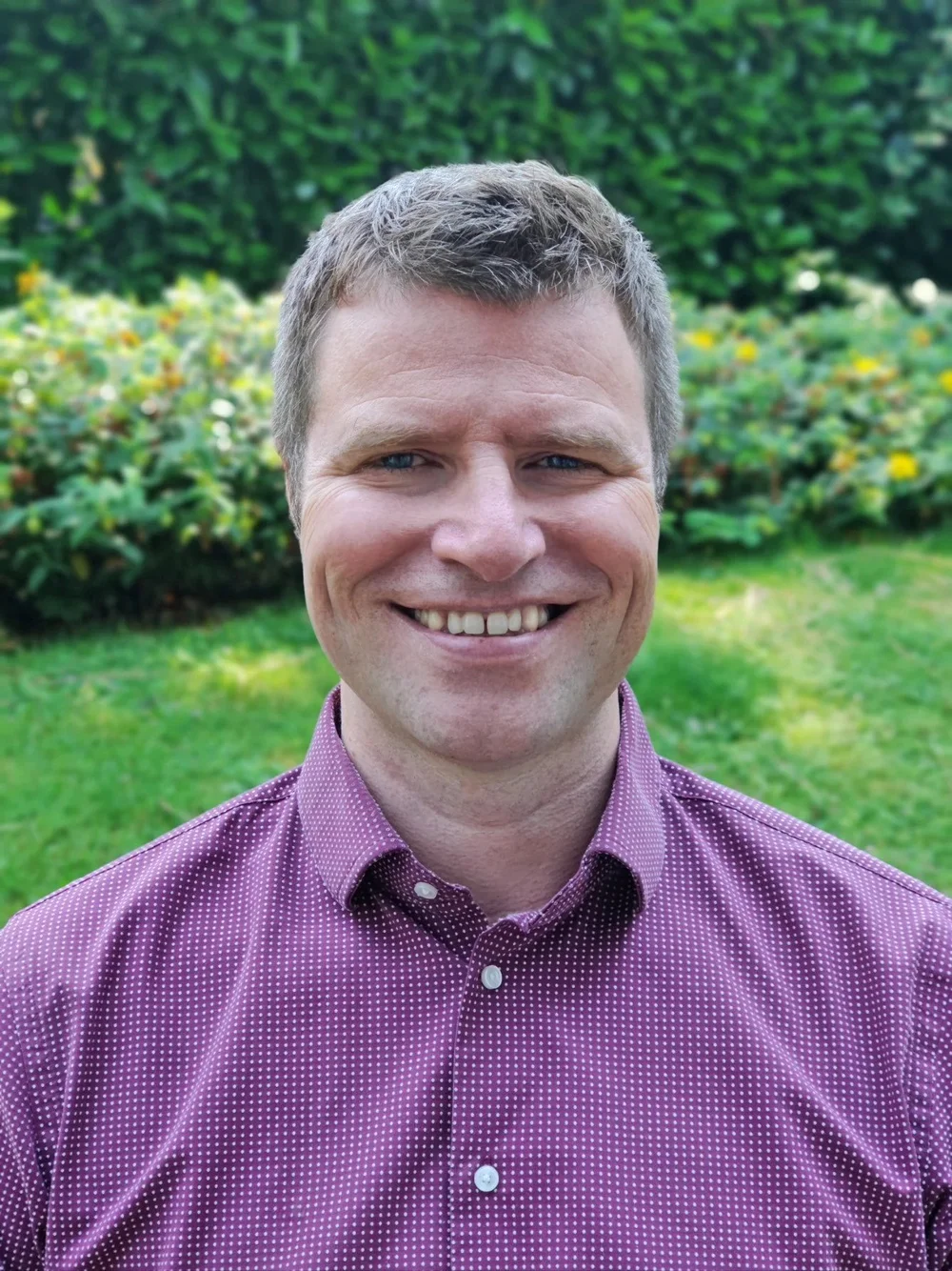 Paul Walsh, LMFT, smiling outdoors in a green garden
