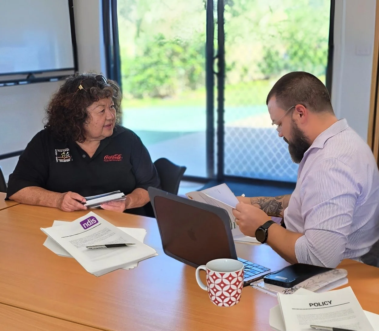A woman and a man are sitting at a table having a Plan Management discussion.