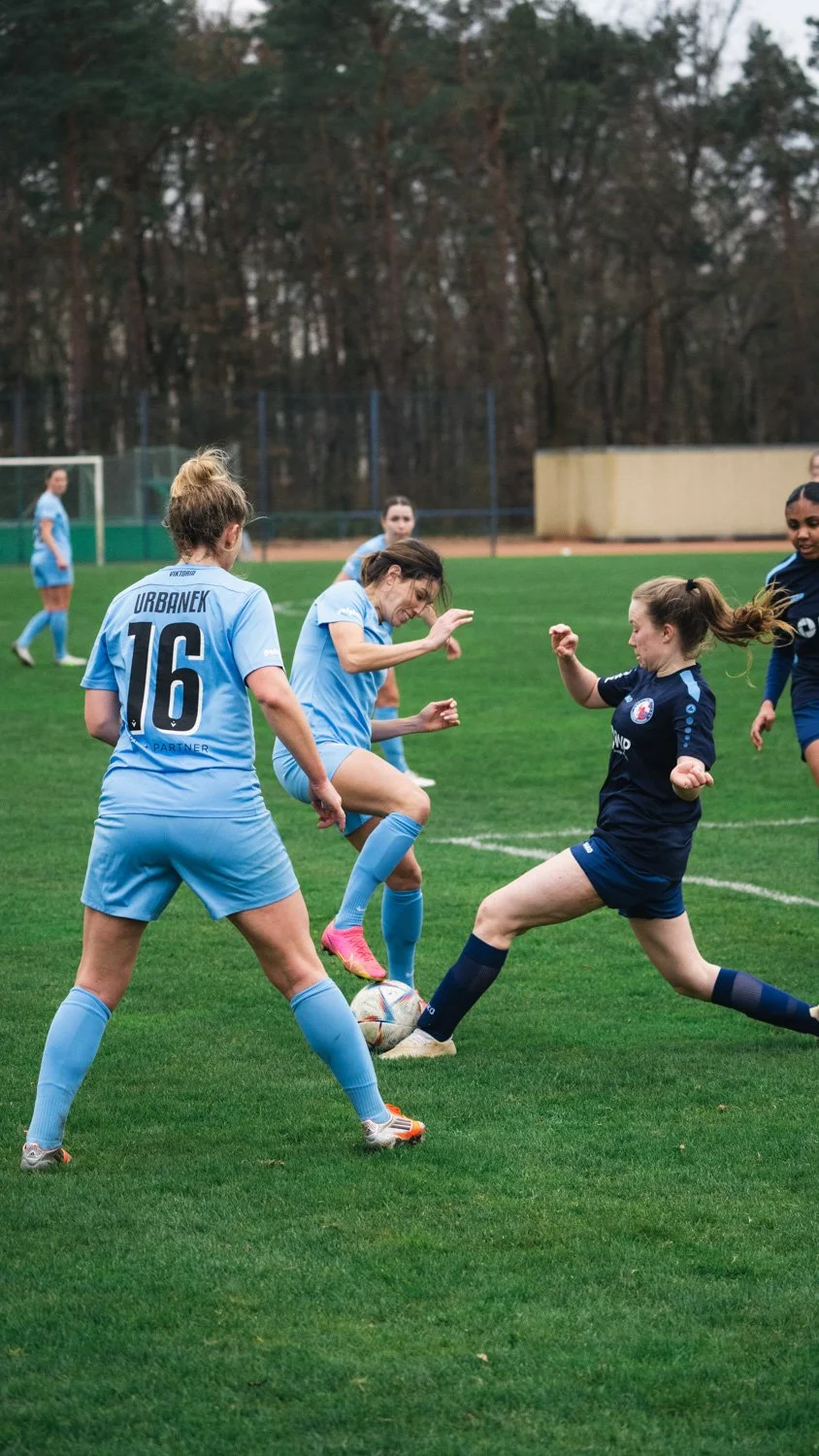 Emotional football photography capturing players of Viktoria Berlin after the final whistle, highlighting exhaustion, relief, and team spirit.