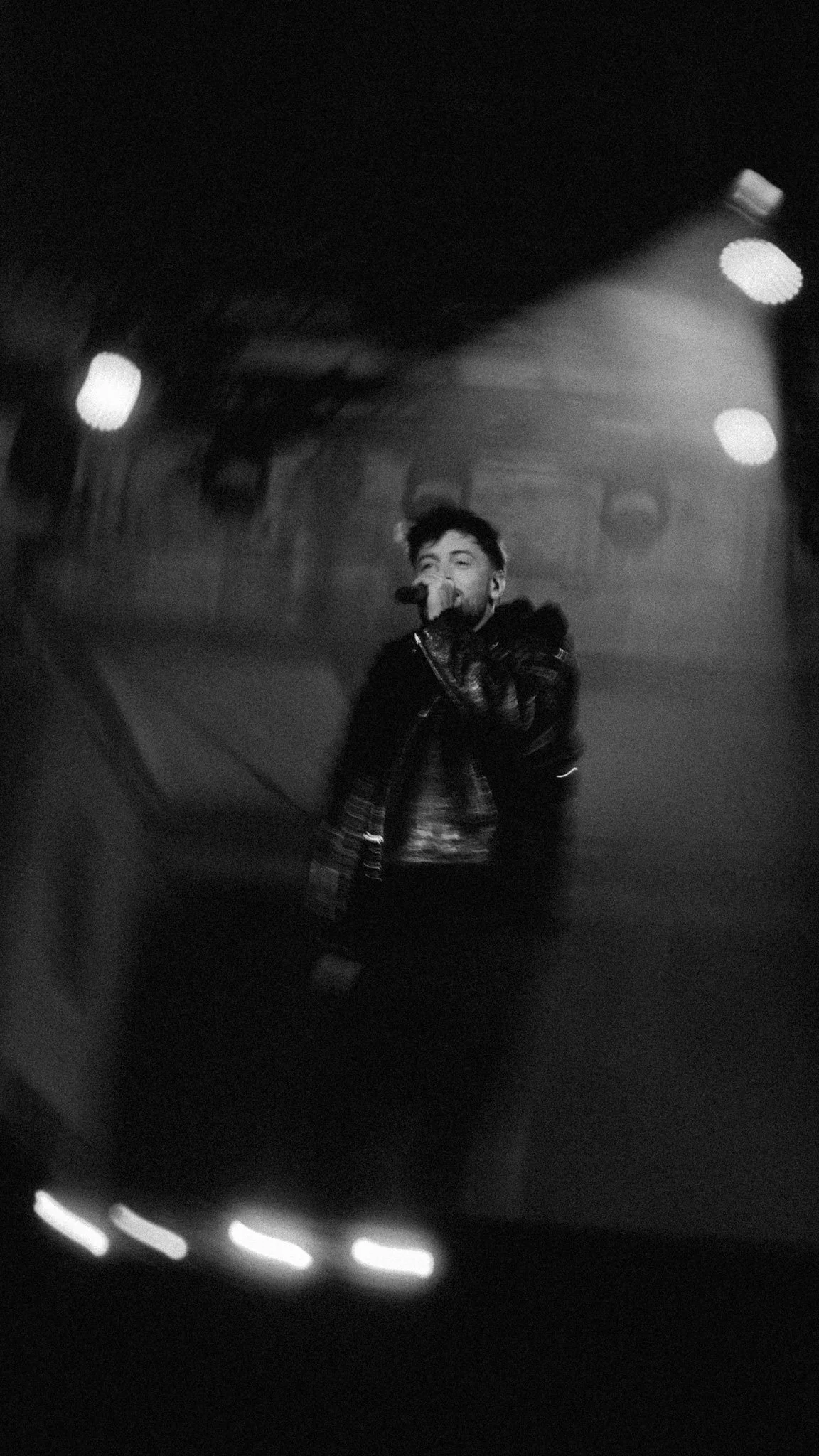 Dynamische Konzertaufnahme von Bausa in Bewegung während einer energiegeladenen Live Show in Berlin.