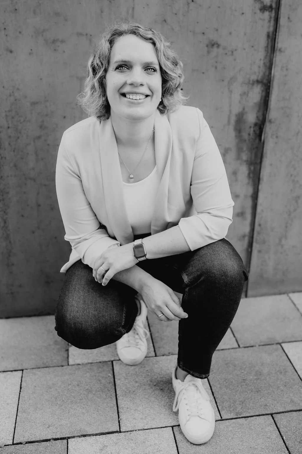 Schwarz-weiß Foto von Meike Hilgemann, hockend vor einer Wand