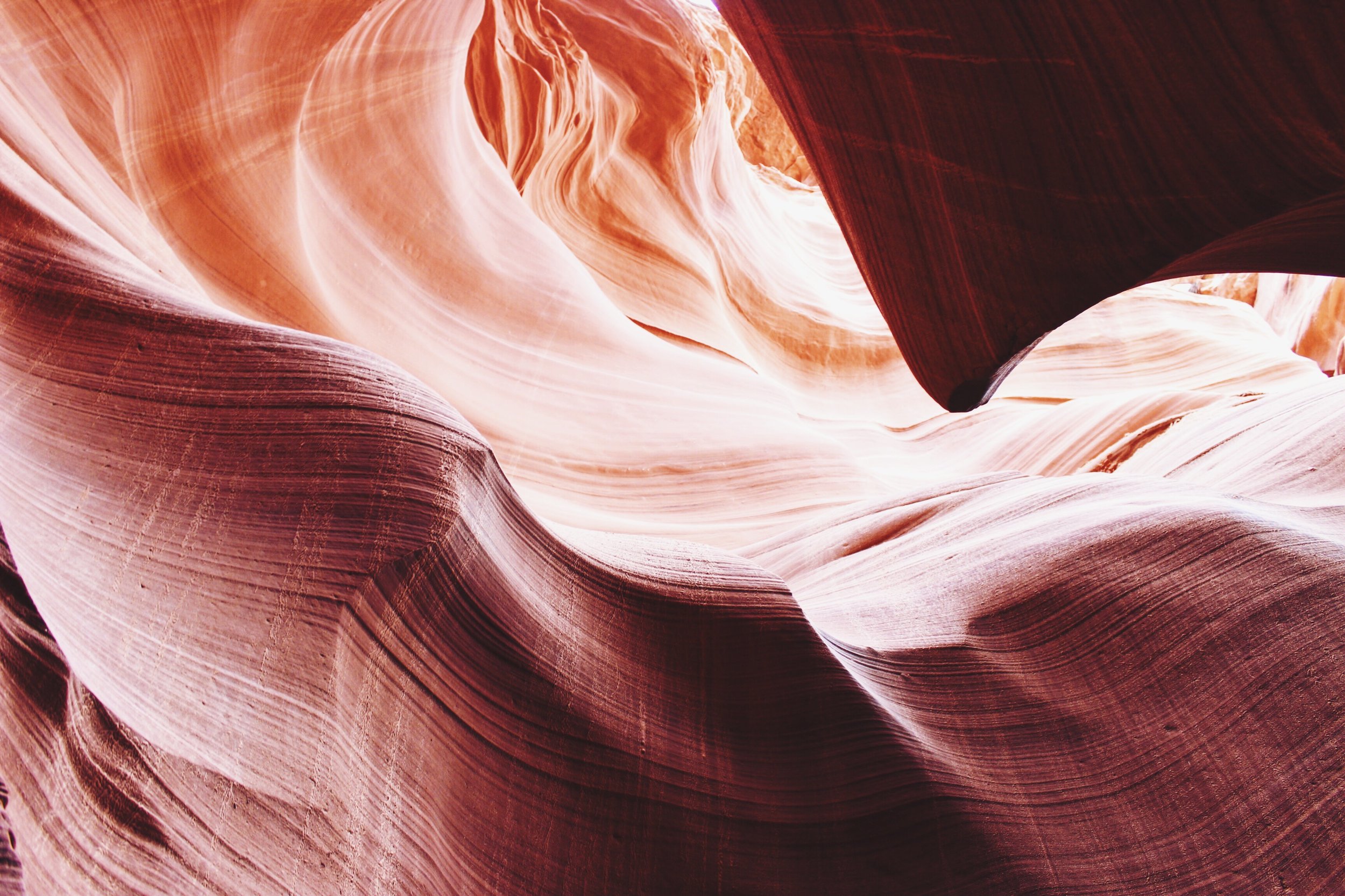 Close-up of colorful, smooth sandstone canyon walls with swirling patterns and striations.