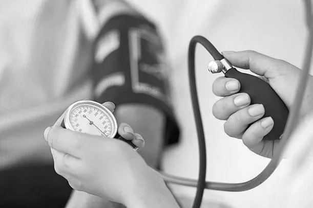 Person measuring blood pressure with a sphygmomanometer and a digital blood pressure monitor.