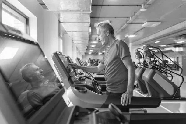 A man on a treadmill in a gym smiling.