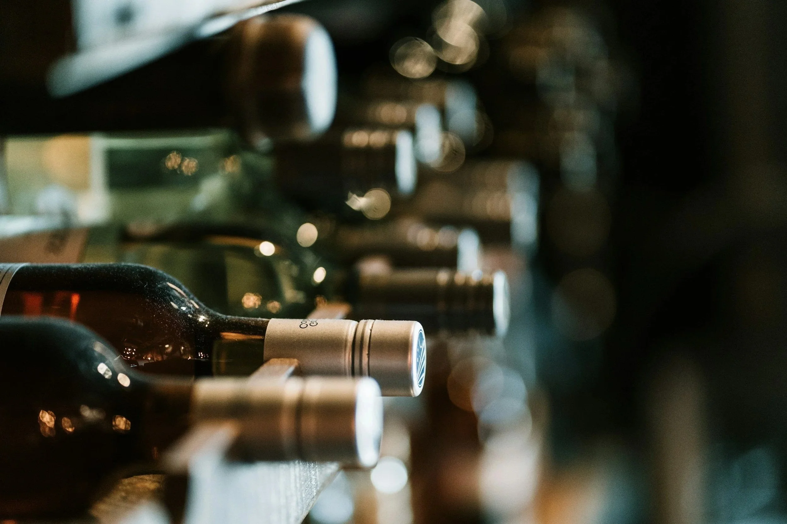 Close-up of wine bottles on a shelf in a dimly lit wine store