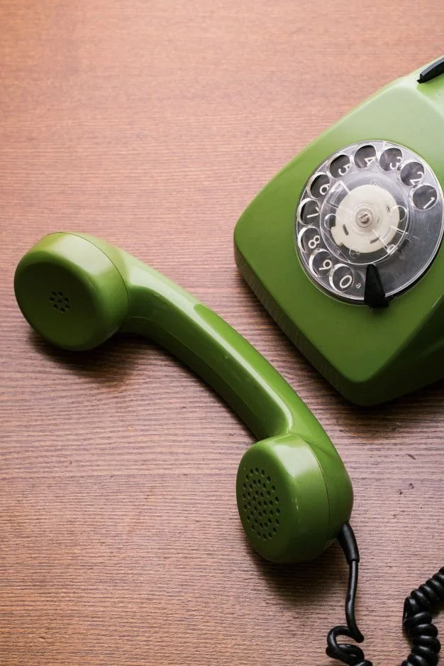 A vintage green rotary phone on a wooden surface.
