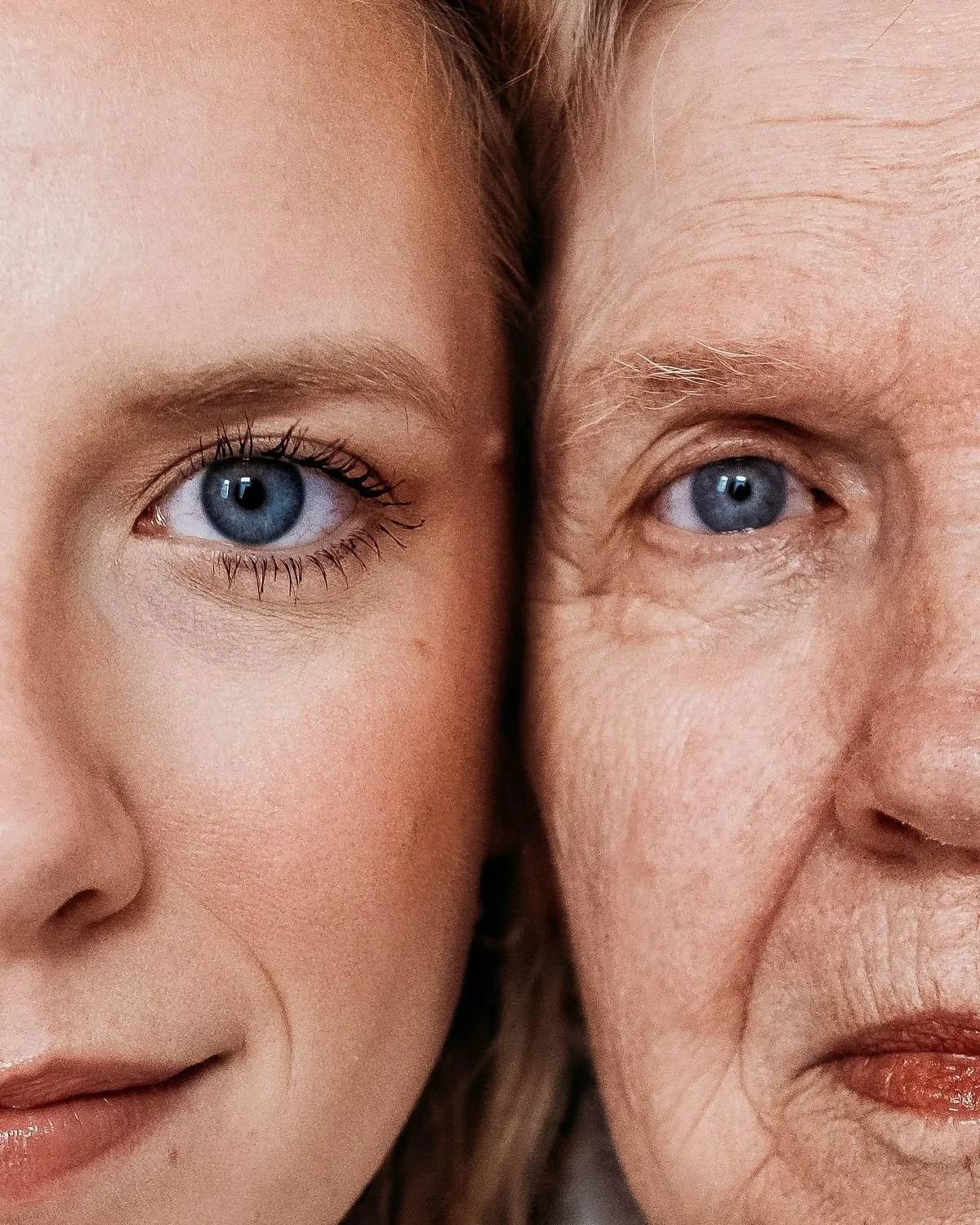 Close-up of a young girl and an elderly woman with blue eyes, faces close together, showing their right sides.