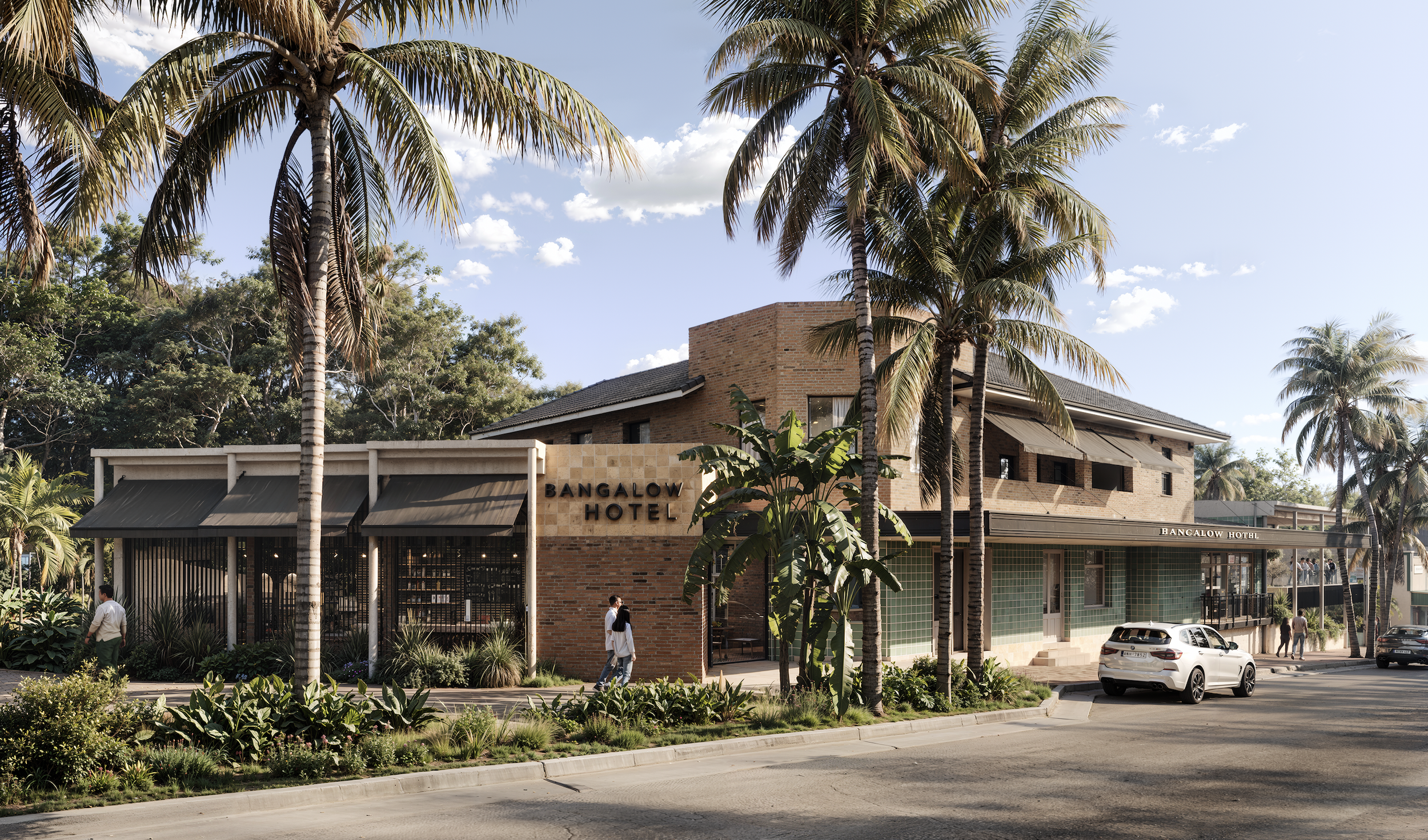 A street view of the Bangalow Hotel, a building with a mix of brick and green-tiled walls, surrounded by tall palm trees, with people walking on the sidewalk and cars parked along the street under a sky with scattered clouds.