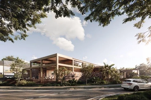Modern hotel building with outdoor seating area, palm trees, and cars parked in front, under a partly cloudy sky.