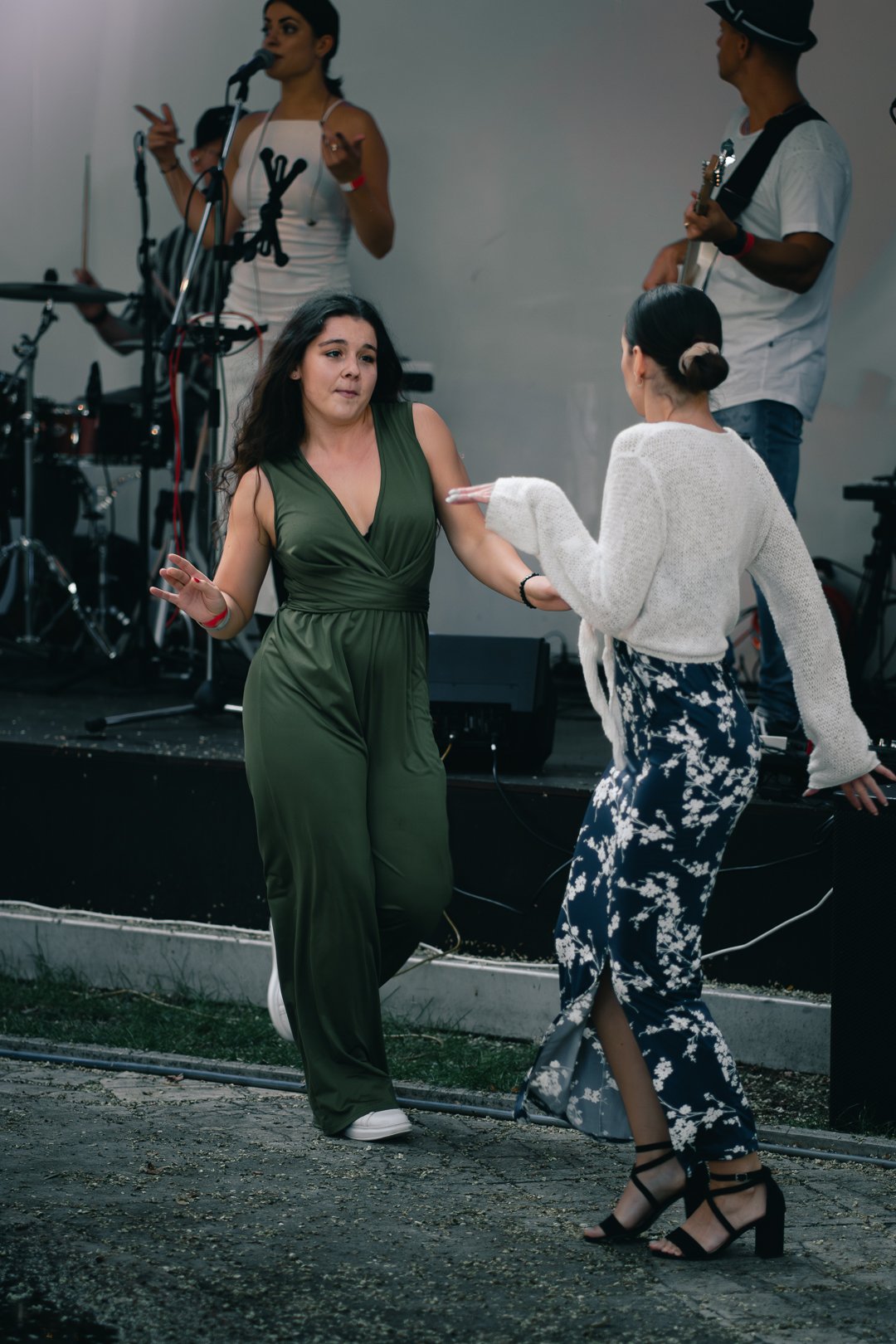 Two women dancing in front of a band playing live music indoors.