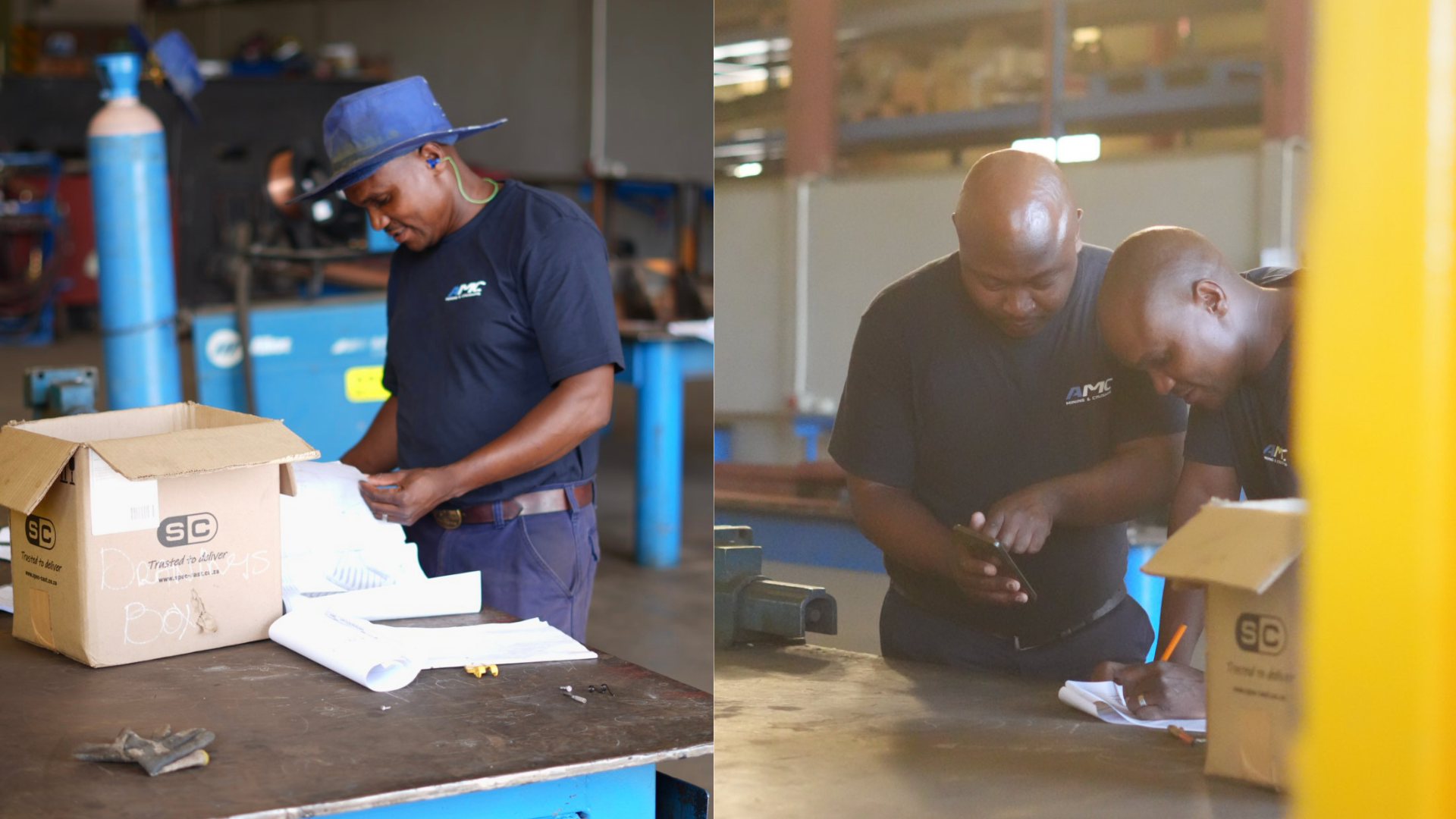 Two men wearing dark blue shirts working in an industrial workshop, looking at notes or a tablet, with various tools and equipment on the workbench.