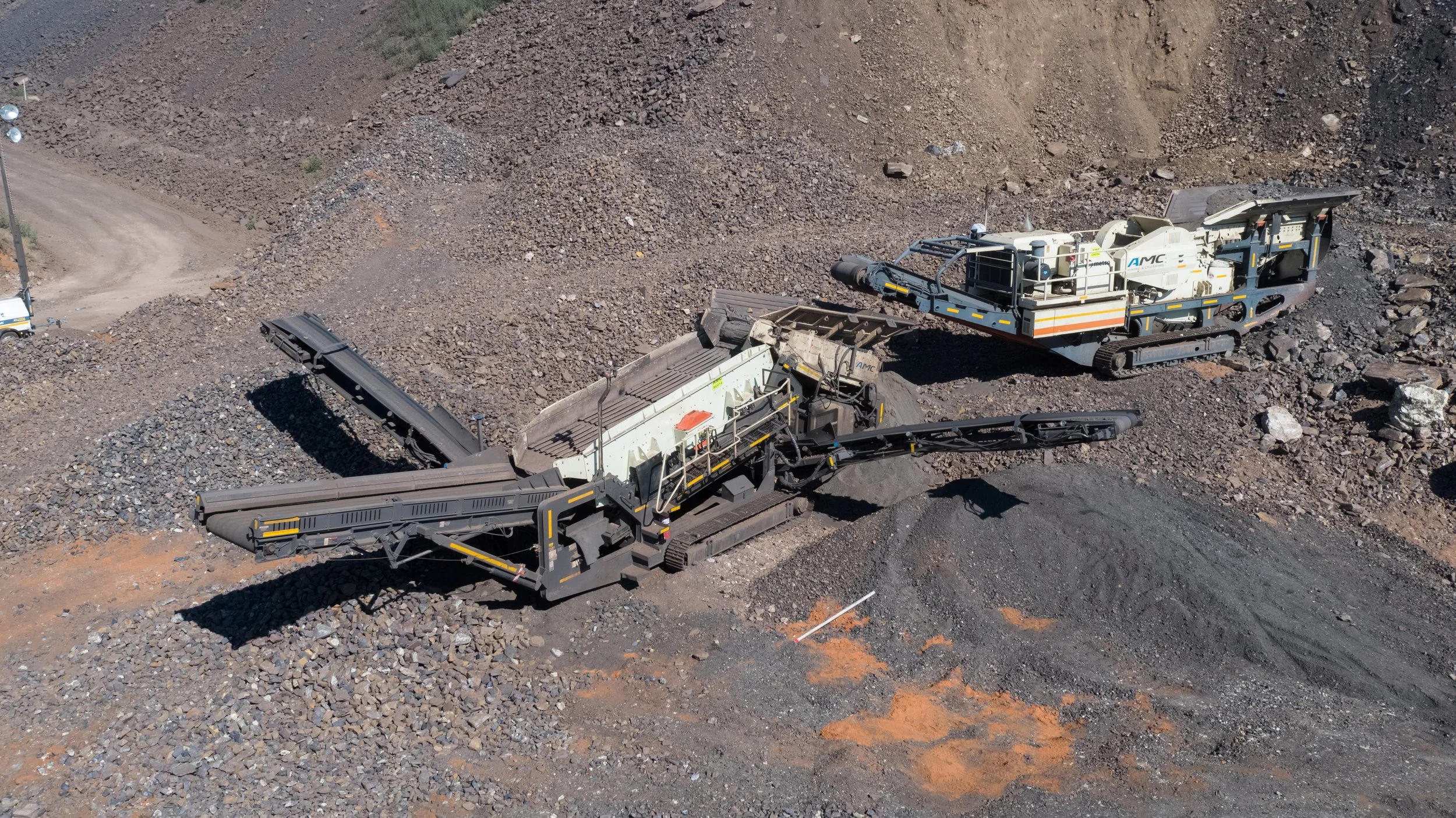 Large industrial mining machines working on a rocky terrain. The machinery is used for crushing and processing minerals or rocks at a mining site.