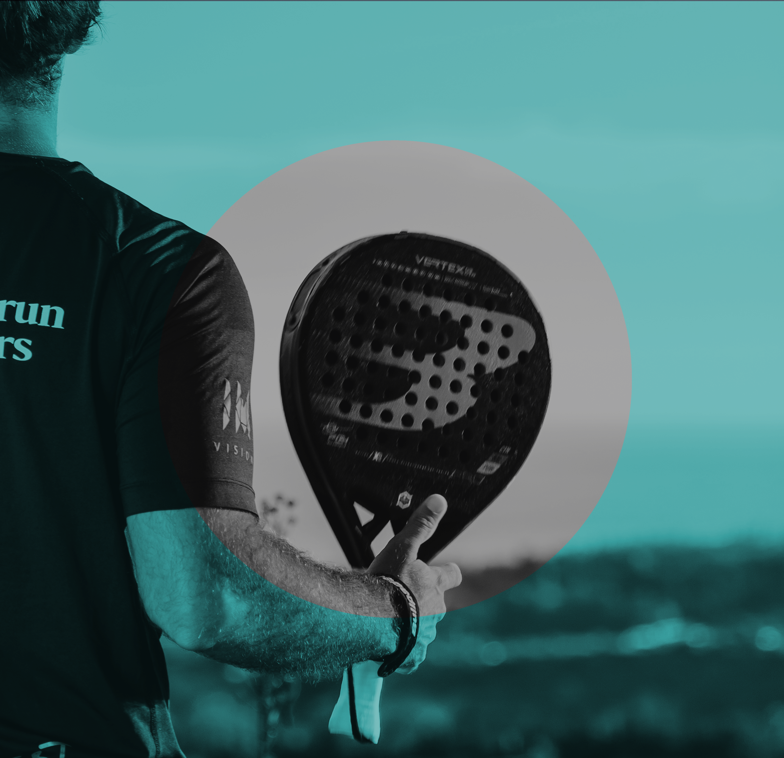 A person holding a padel racket outdoors.