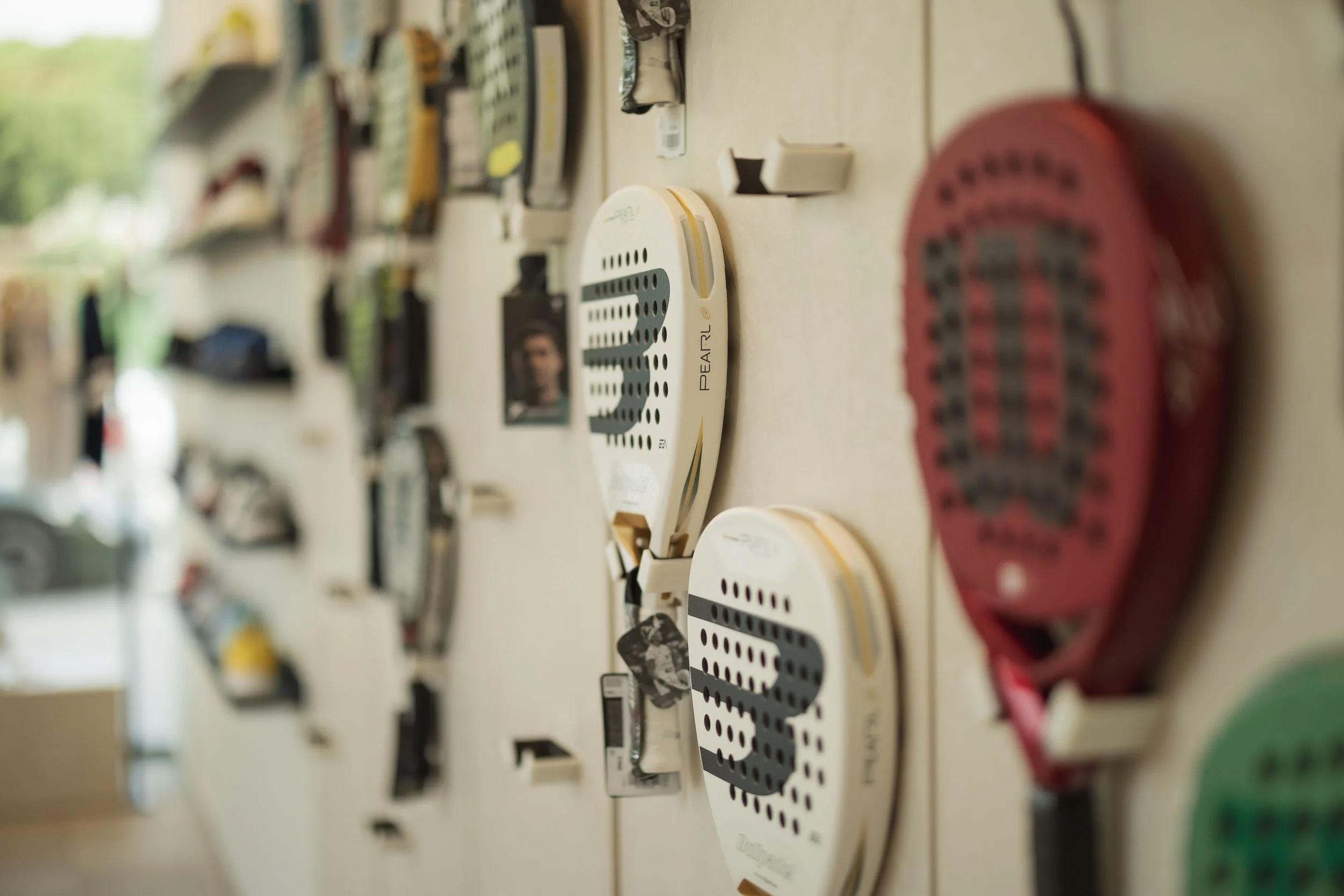 Close-up of a wall display featuring various filing tags, labels, and organizational items, with some in black and white photos, and a blurred background of a window and greenery.