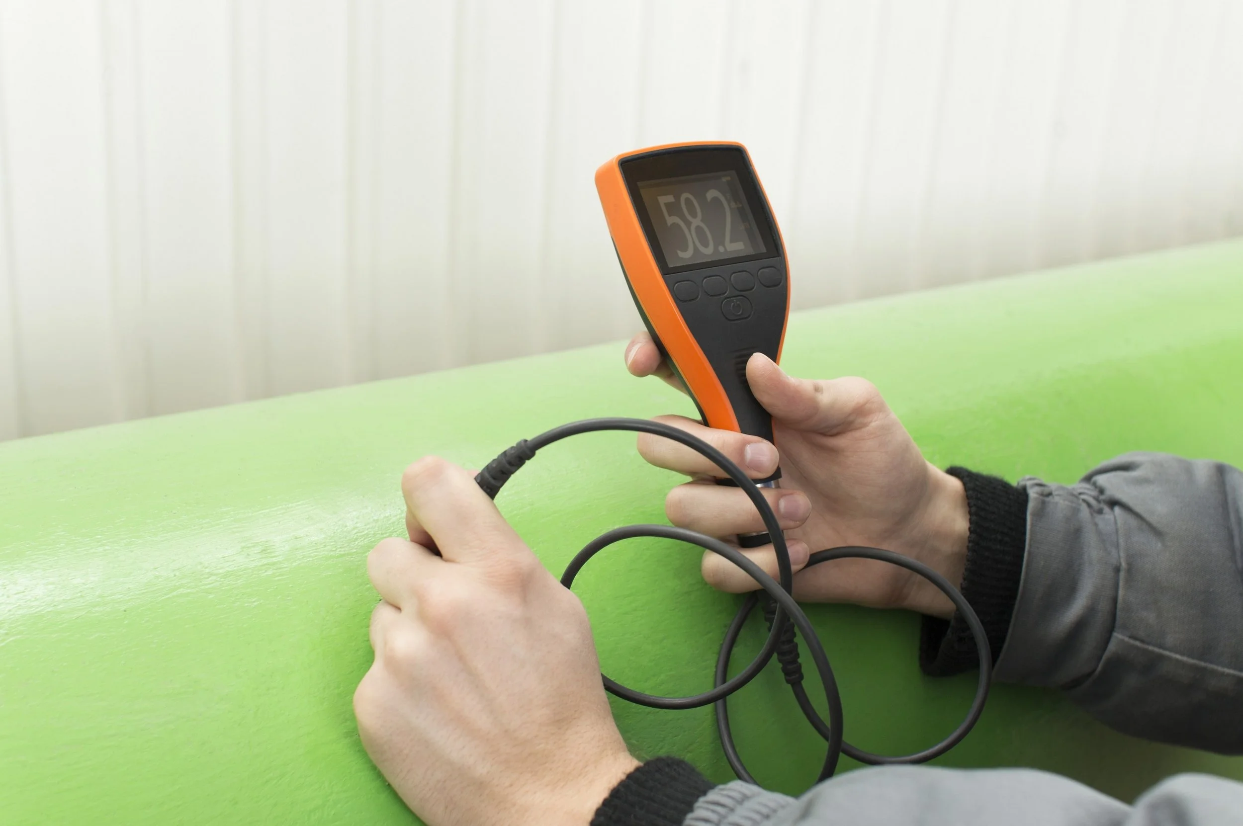 Person measuring surface temperature with infrared thermometer, showing 58.2 degrees Fahrenheit.