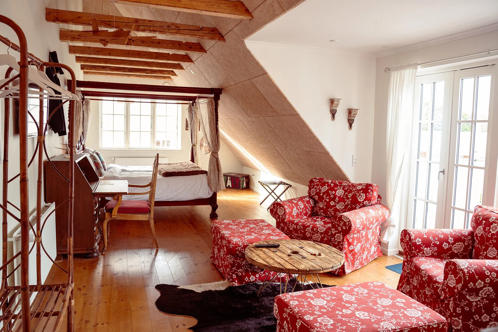 Loftssuite med åbne bjælker, himmelseng, røde lænestole