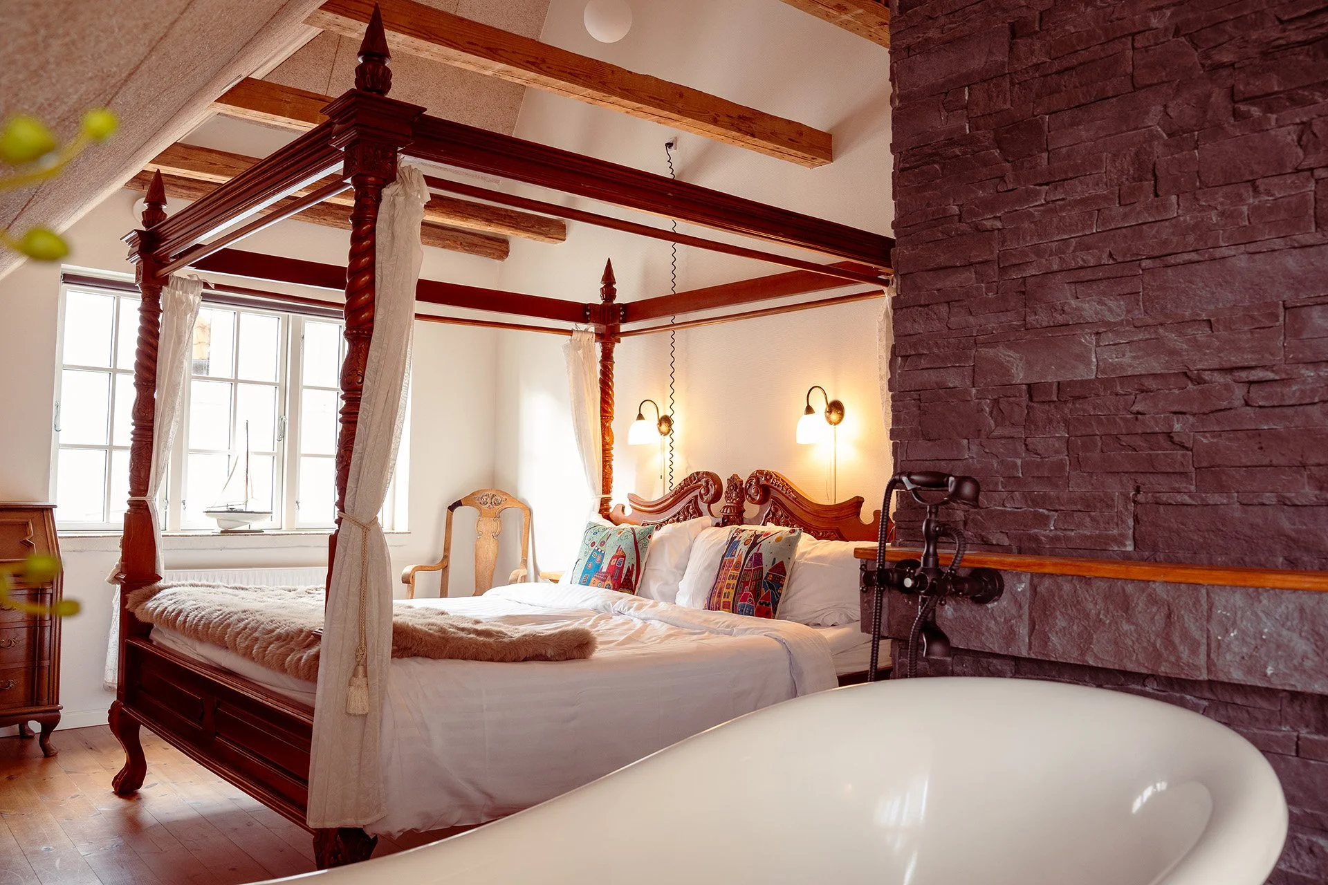 Mørk himmelseng, fritstående badekar, stenmur, mansardloft