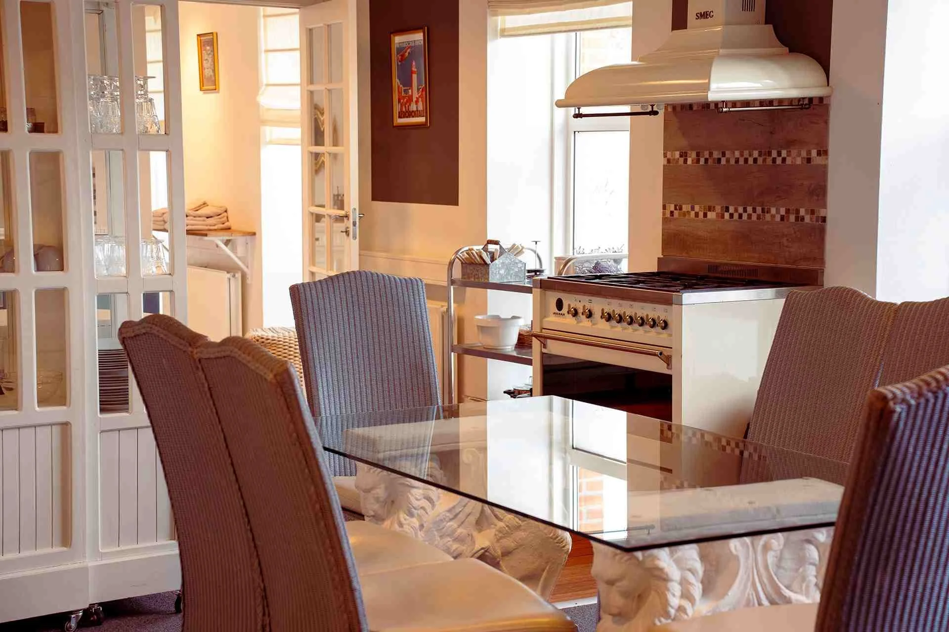 Elegant spisekøkken, glasspisebordet, rotting stole, professionelt komfur