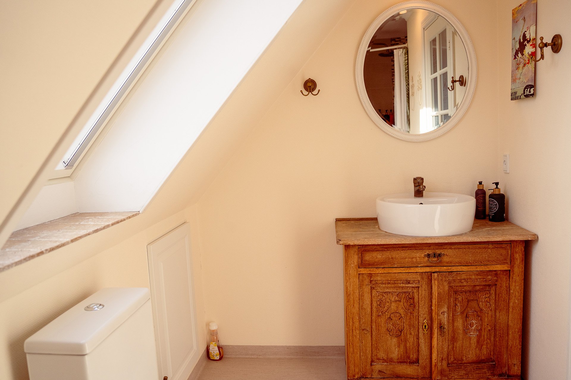 Rundt ovalt spejl, håndvask, trækommode, mansardvindue