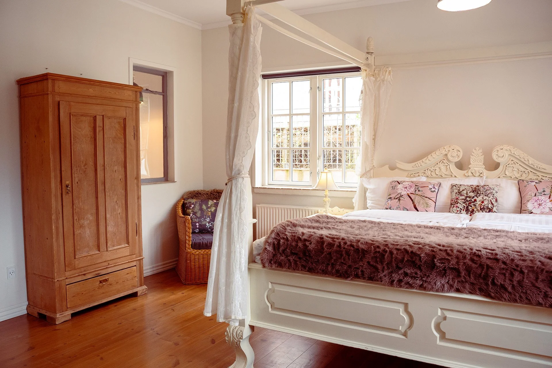 Antikt træskab, hvid himmelseng, rosa puder, dagslys