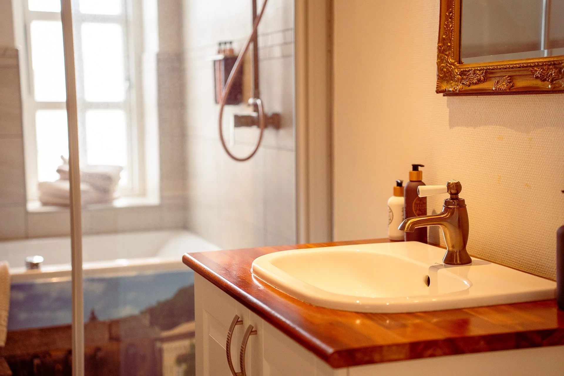 Håndvask detalje, guldramme spejl, træbordplade, messing armatur