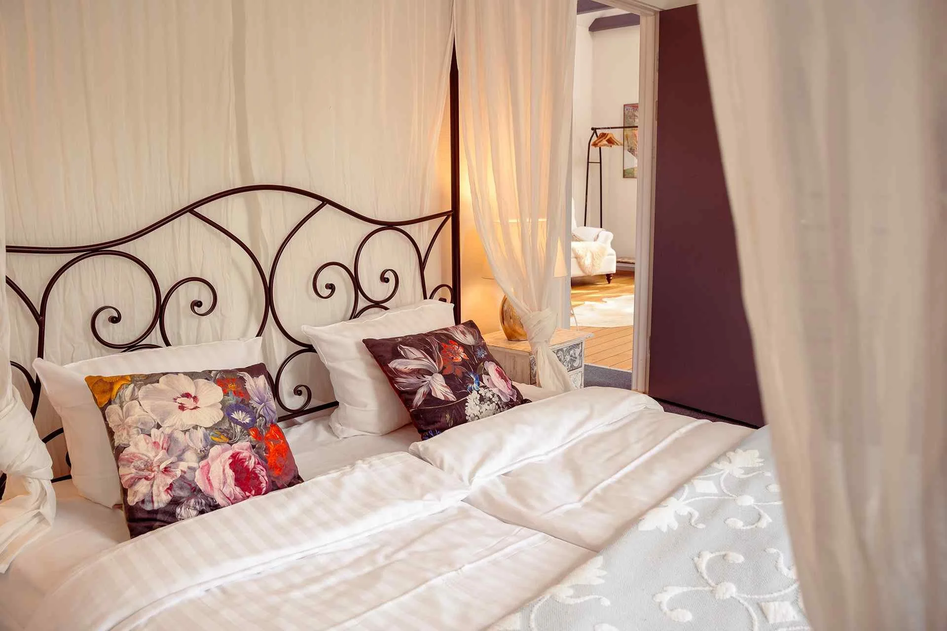 Smedejernseng med blomstrede puder, hvid baldakin, romantisk stemning