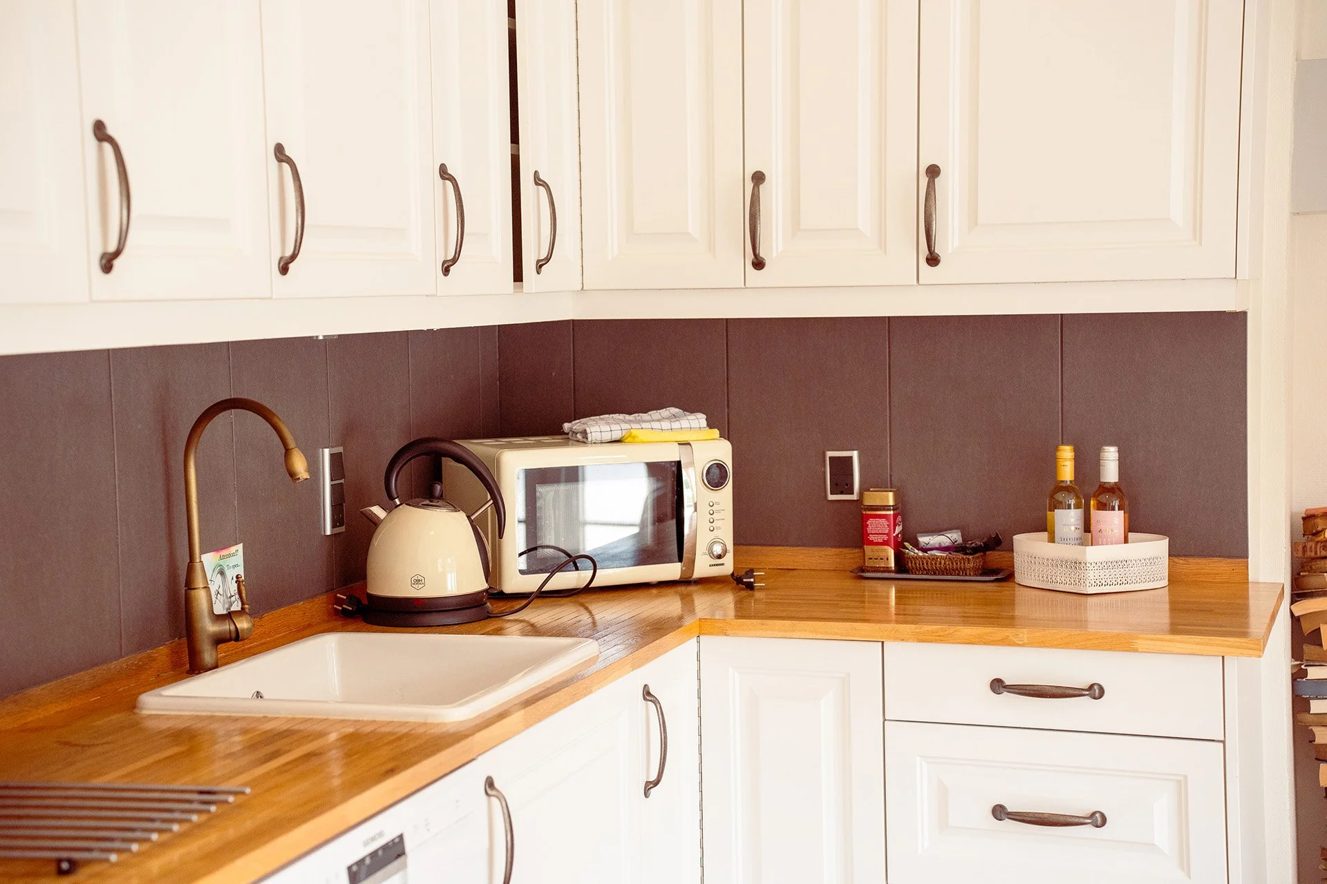Hvidt køkken, træbordplade, elkedel, microovn