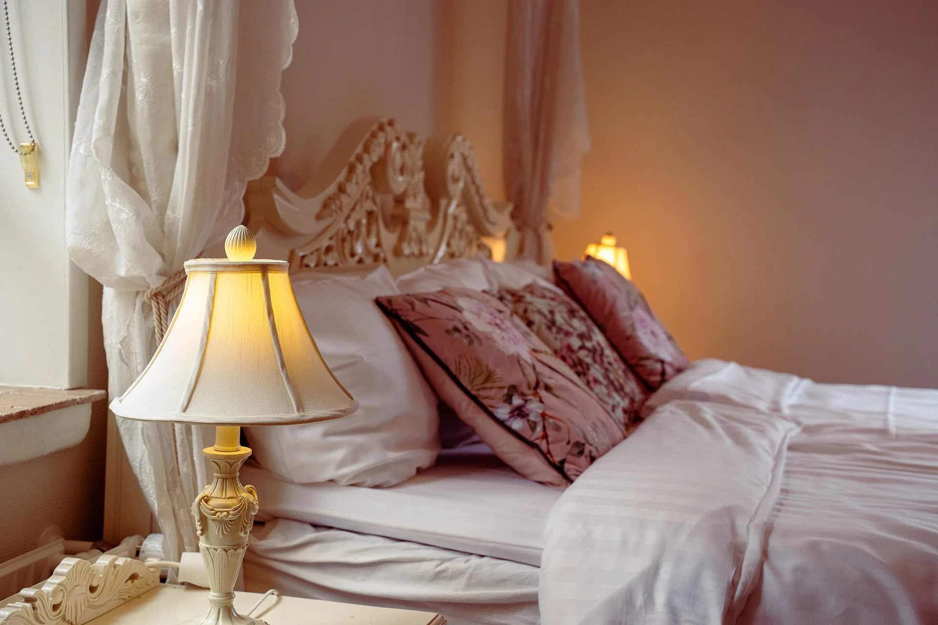 Brandmesterenns Vagtslue, udskåret hvid sengegavl, rosa puder, sengelampe