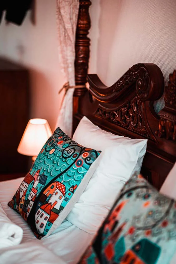 Udskåret himmelseng, folkekunst-puder, hvidt sengetøj