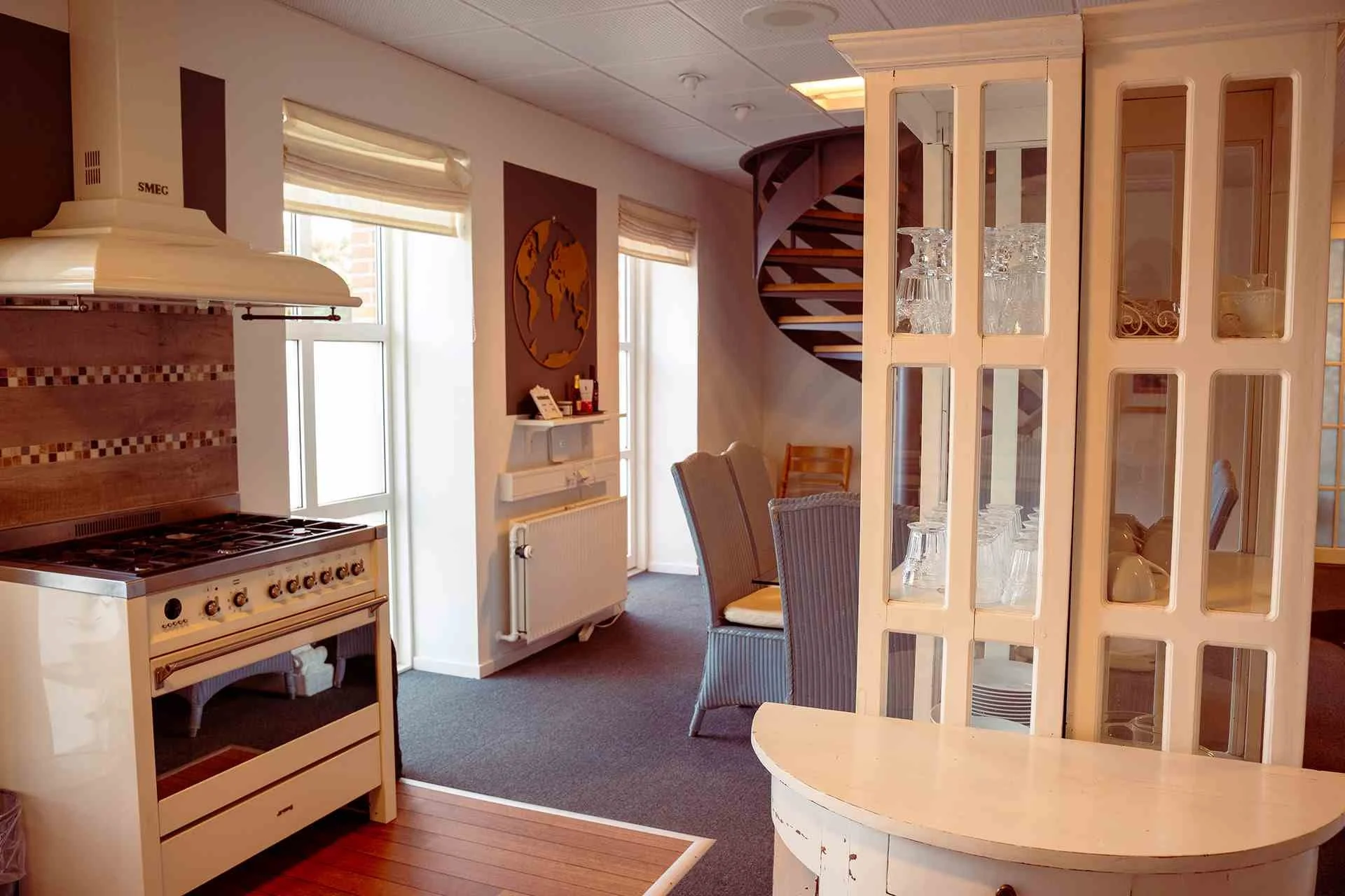 Åbent køkken, professionelt komfur, vitrineskab, verdenskort, industrielt loft