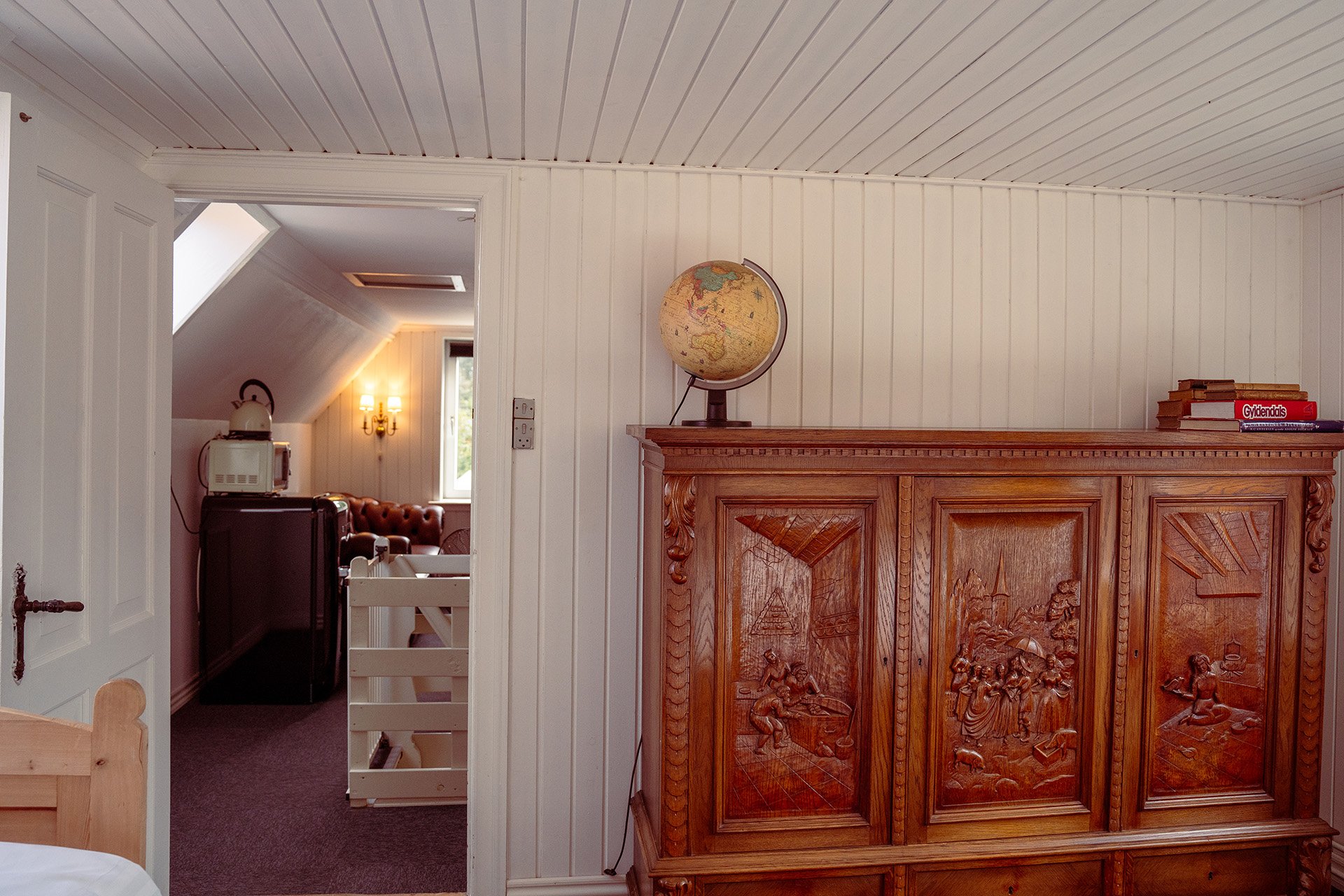 Udskåret antikt skab med globus, bøger, Chesterfield stue baggrund