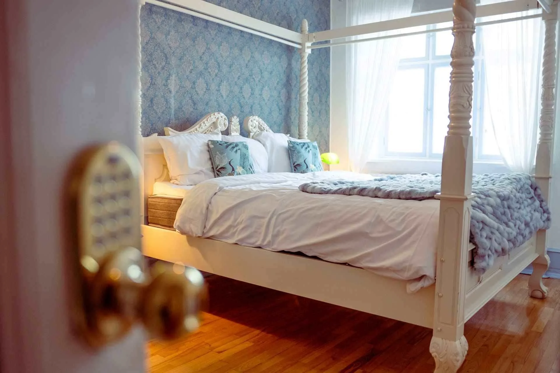 Hvid himmelseng, blå tæppe, damask tapet, dagslys