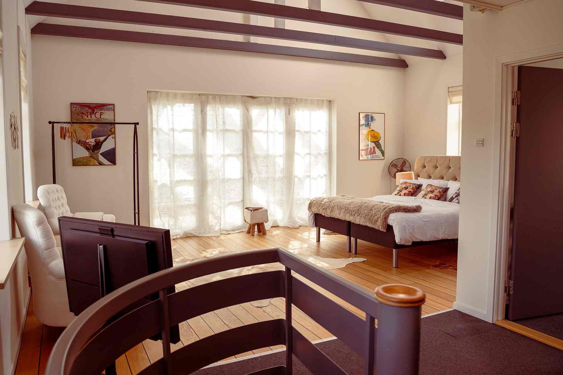 Grand Aviator Suite, åbne bjælker, franske døre, vintage rejseplakater, dobbeltseng