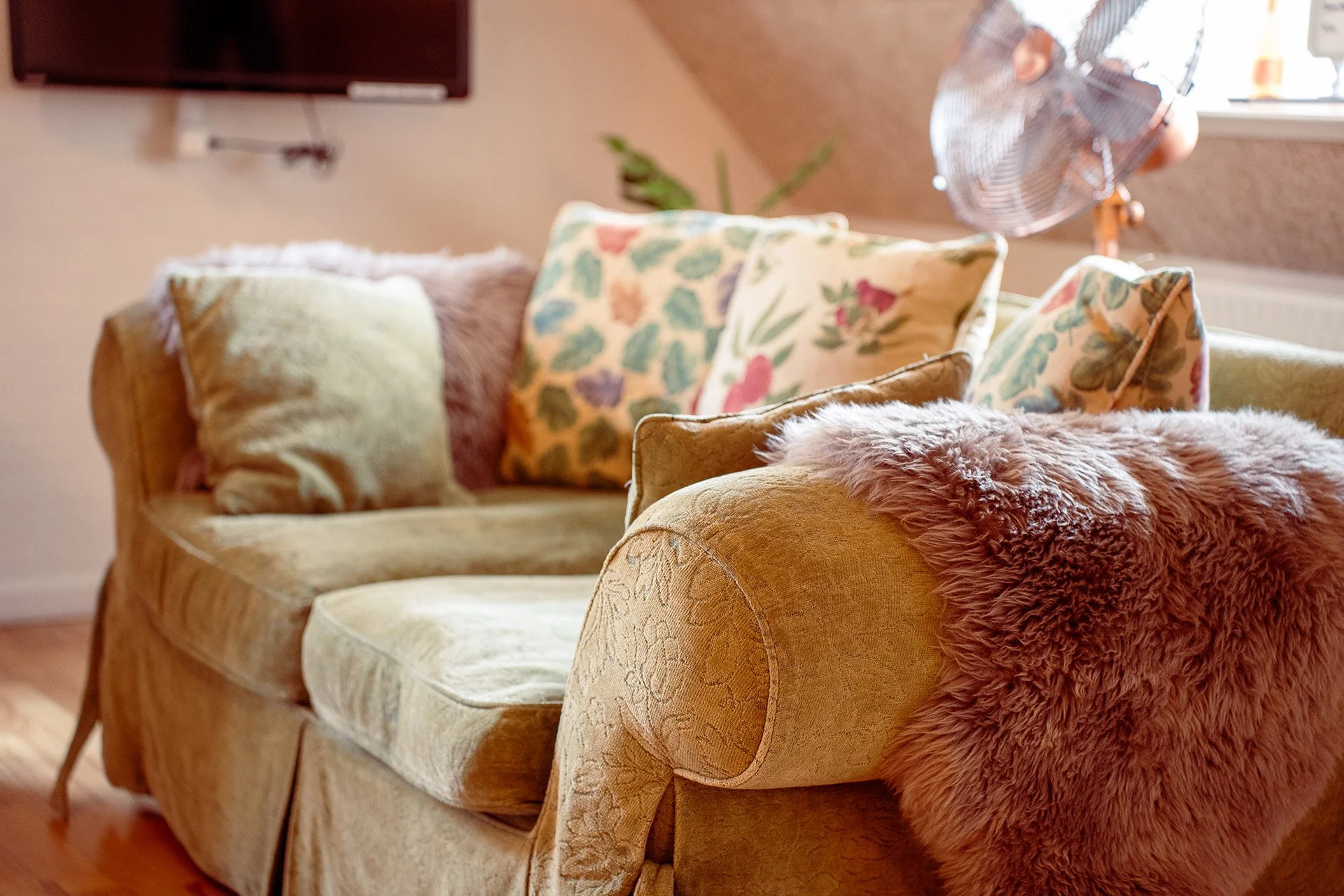 Grøn sofa, blomstrede puder, pelstæppe detalje