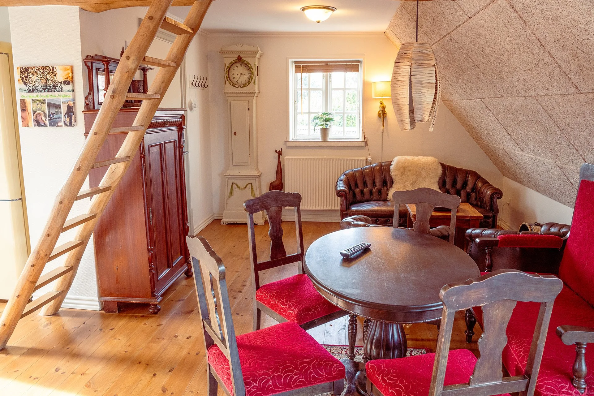 Loftsstige, røde stole, rundt bord, Chesterfield sofa, penduler