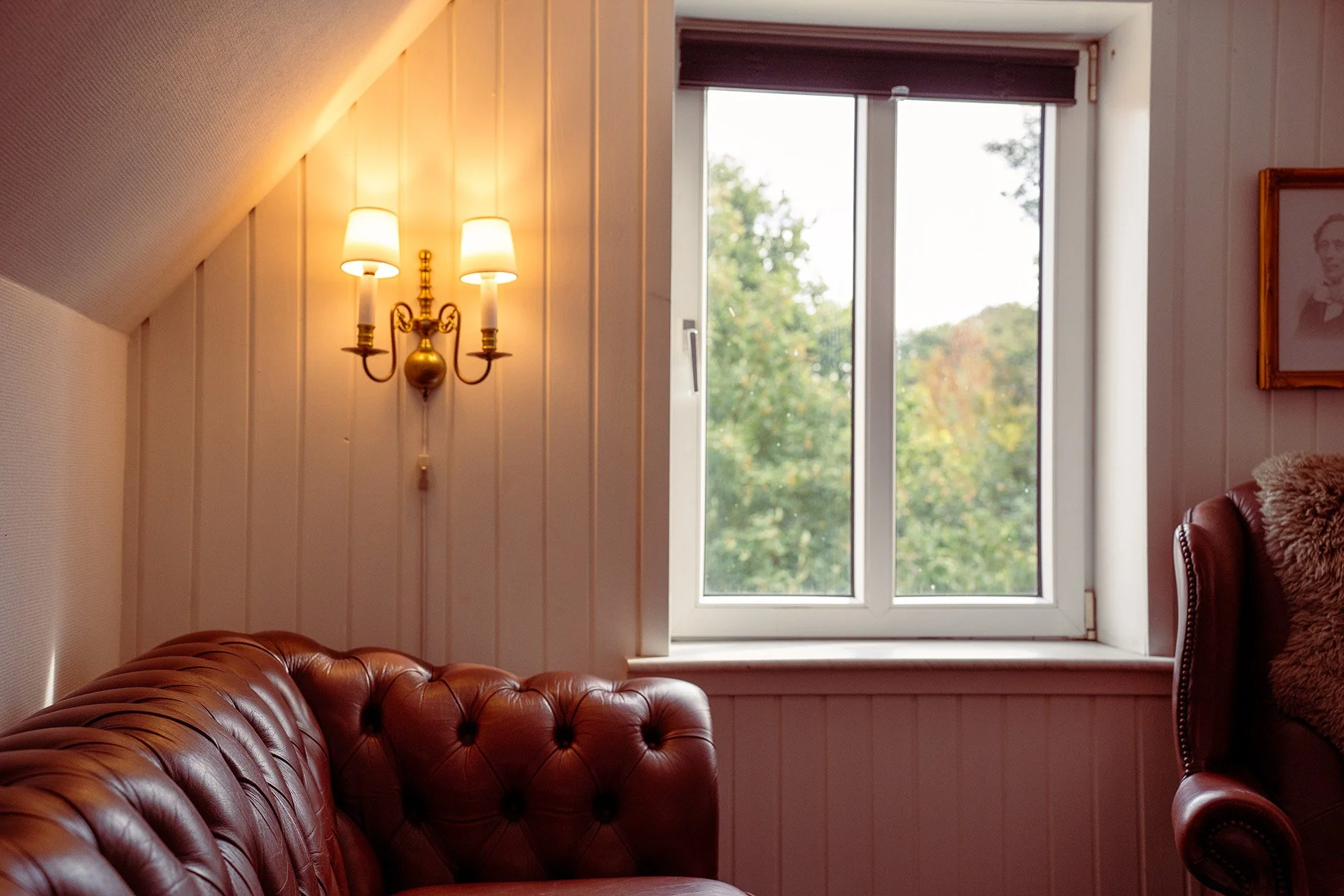 Chesterfield sofa, væglampe, mansardvindue, havudsigt