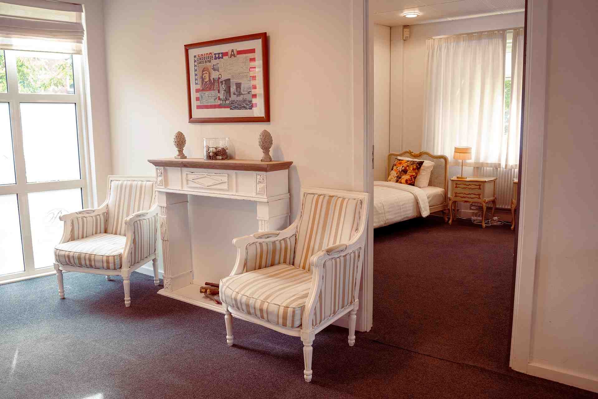 Hvidt skrivebord, stribet lænestol, enkeltvseng, klassisk møblering