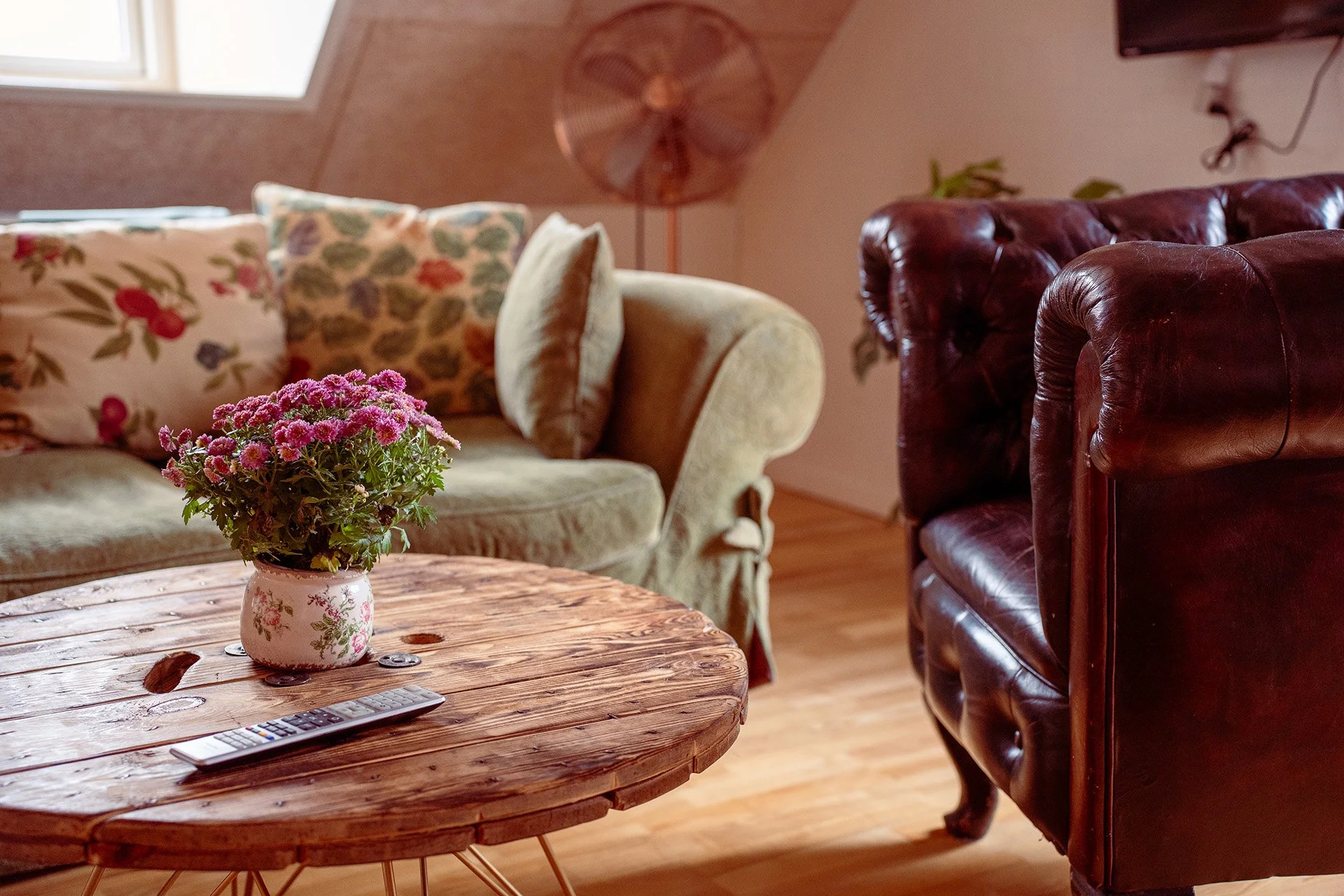 Grøn sofa, blomster, træhjulsbord, Chesterfield detalje