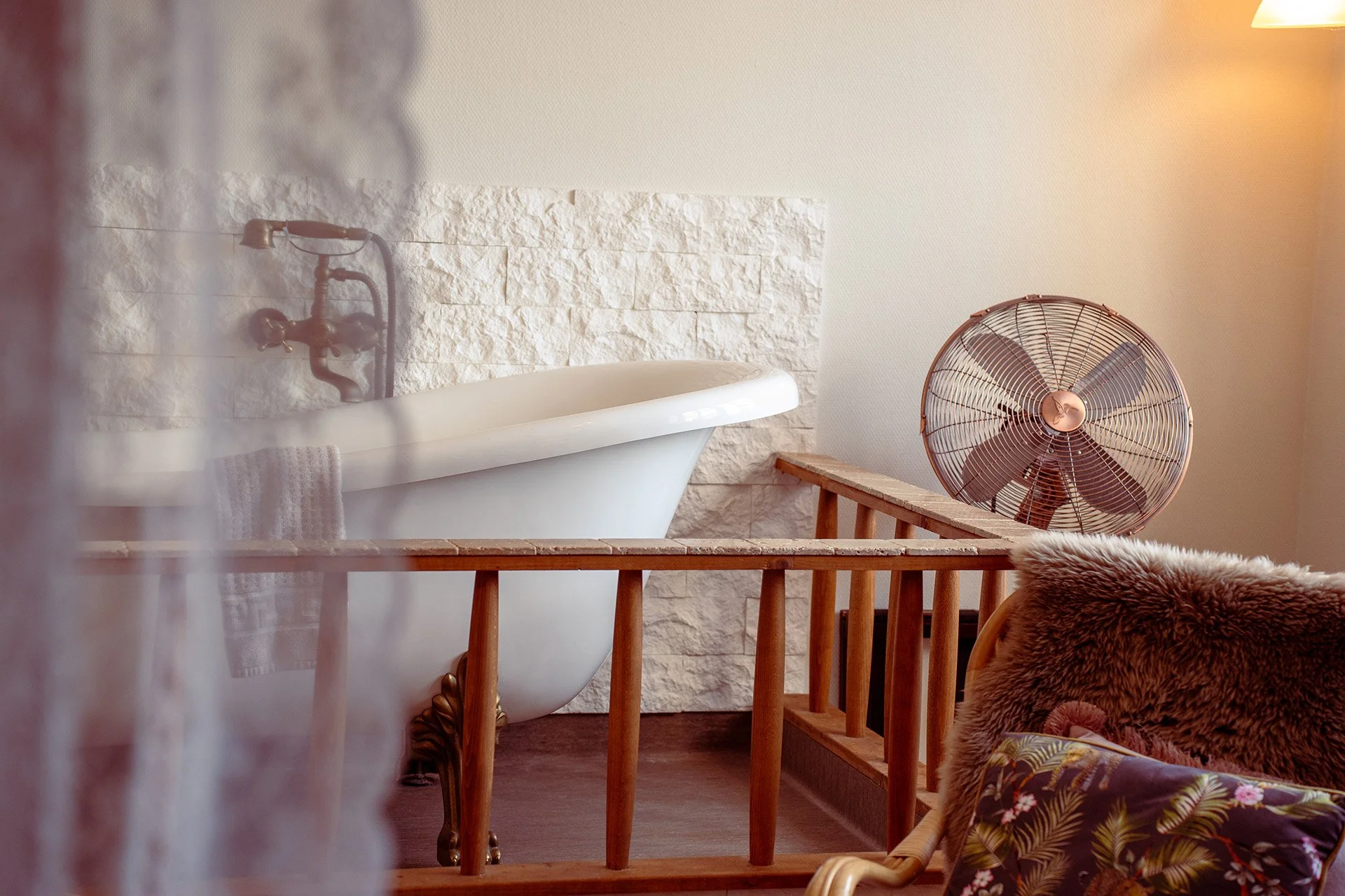 Fritstående badekar, stenmur, ventilator, rotting møbler