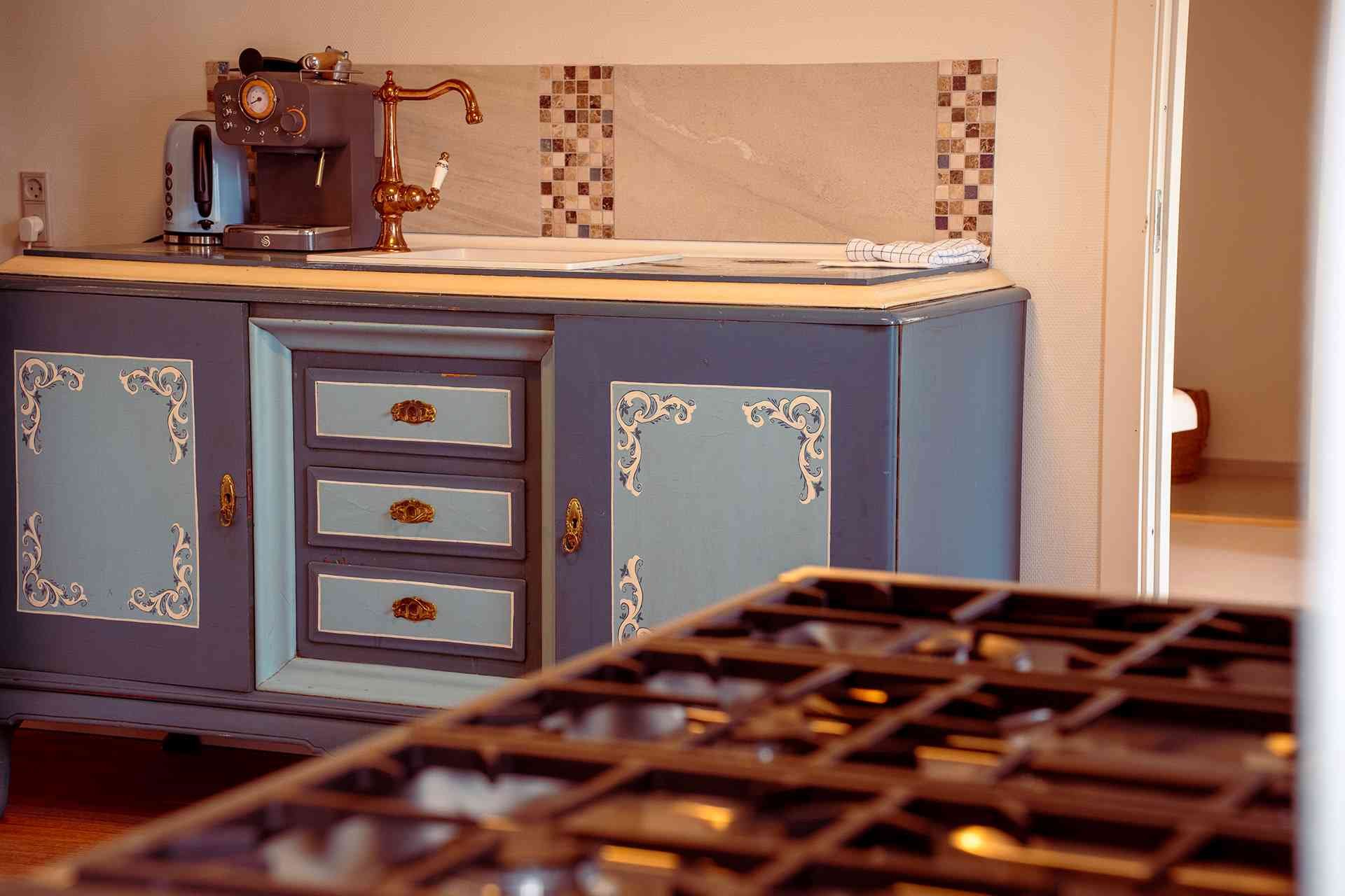 Blåmalet vintage kommode, kobber kaffemaskine, mosaikfliser, bogtryk bakke