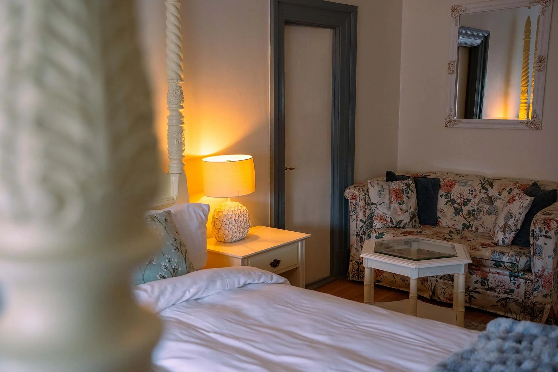 Himmelseng detalje, sengelampe, blomstret sofa baggrund