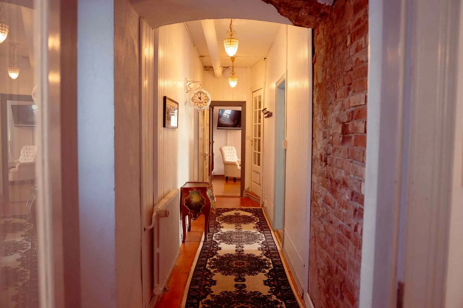 Lang gang, orientalsk løber, murstenvæg, lampelys